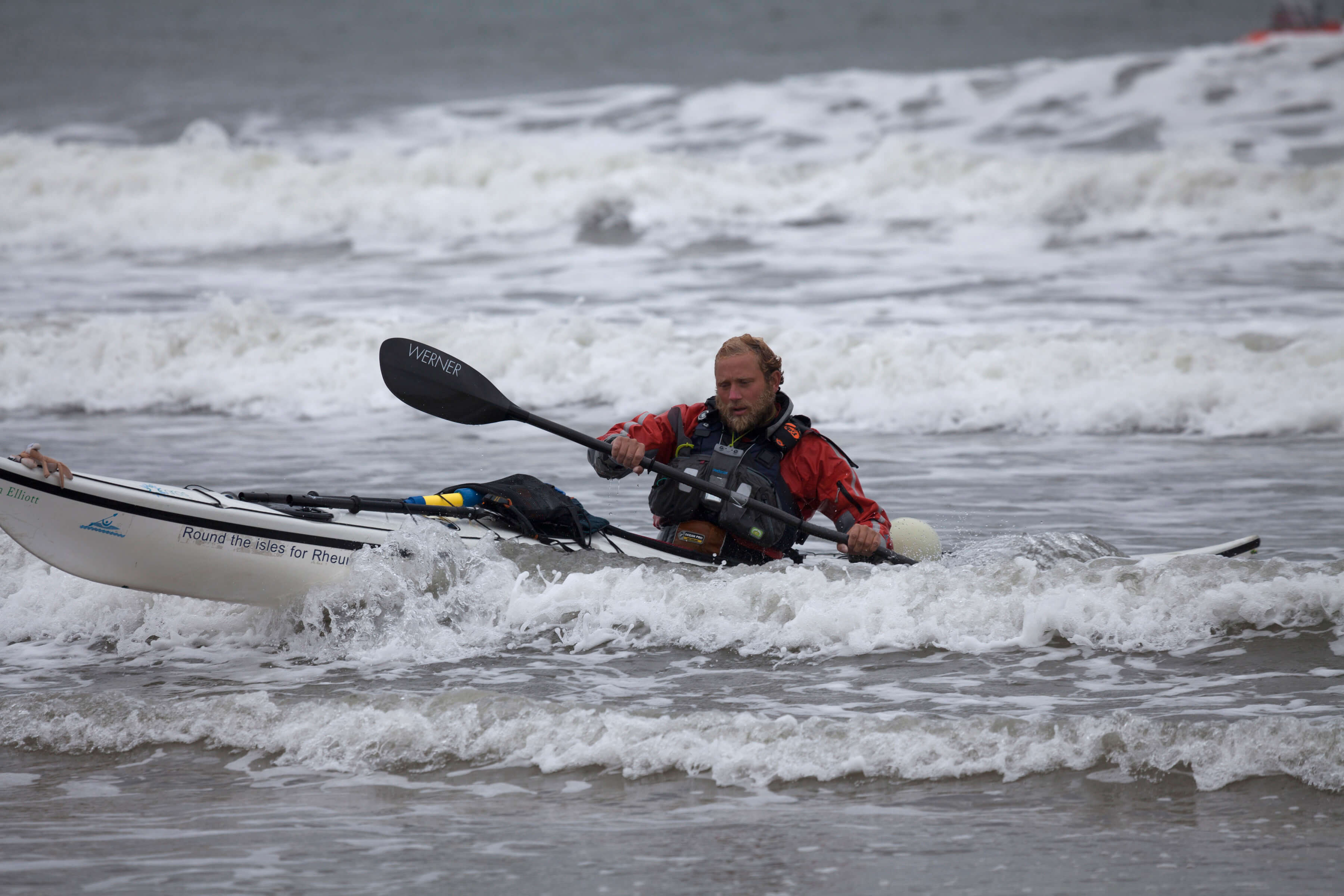 A man kayaking through a choppy sea