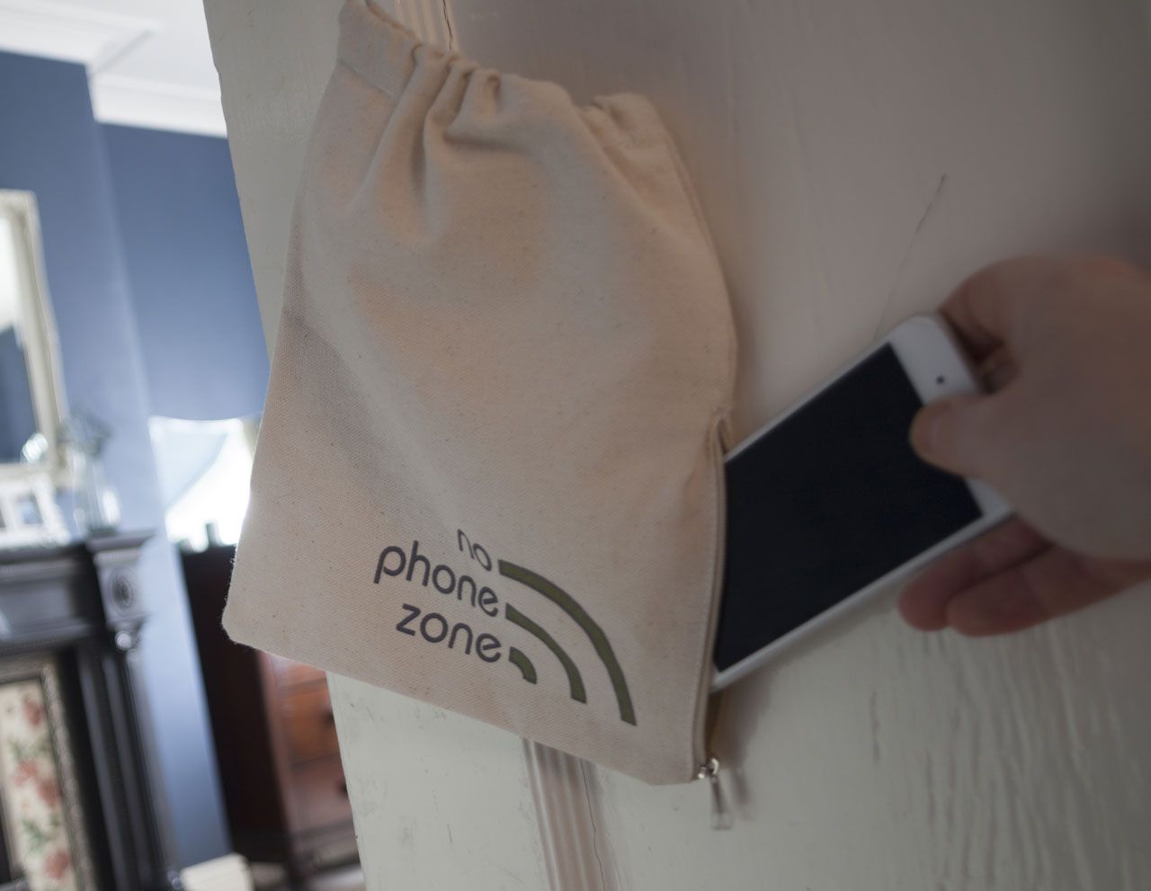 A phone being placed into a bag handing on a door handle
