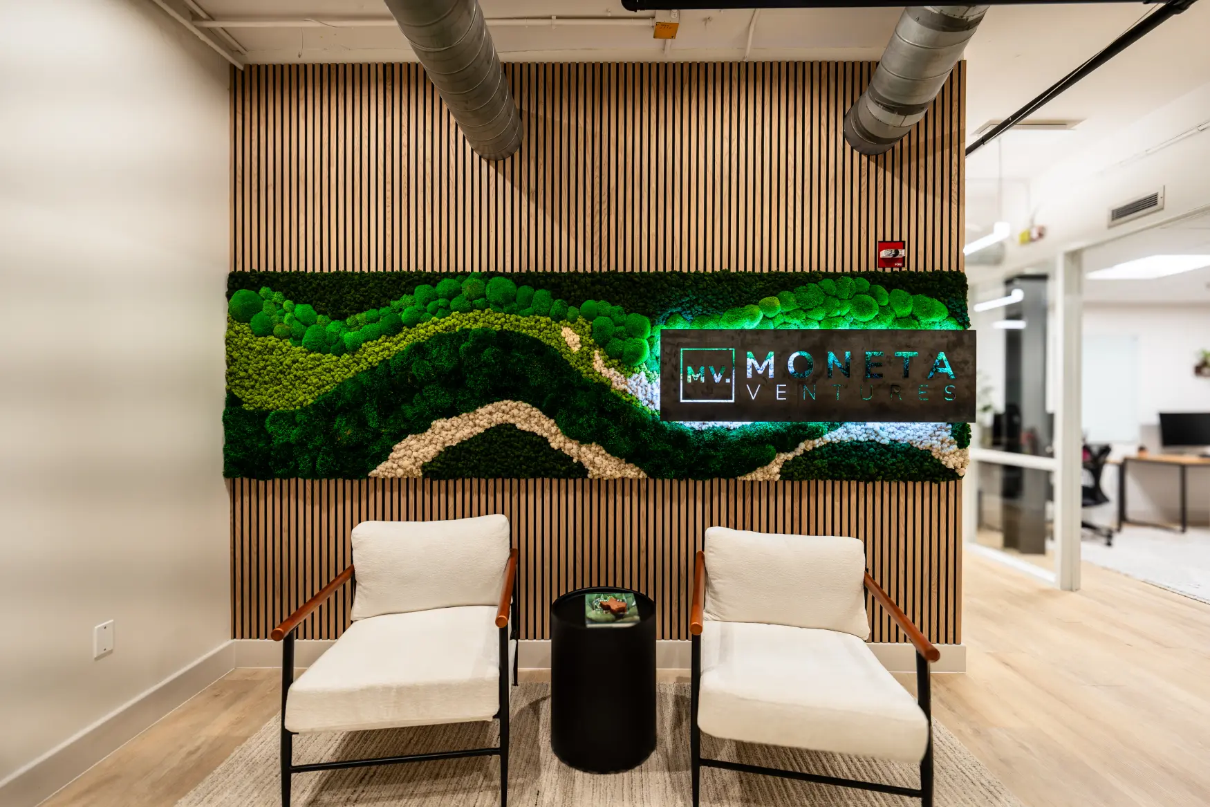 Moneta Ventures 10 foot moss wall with backlit raw steel logo