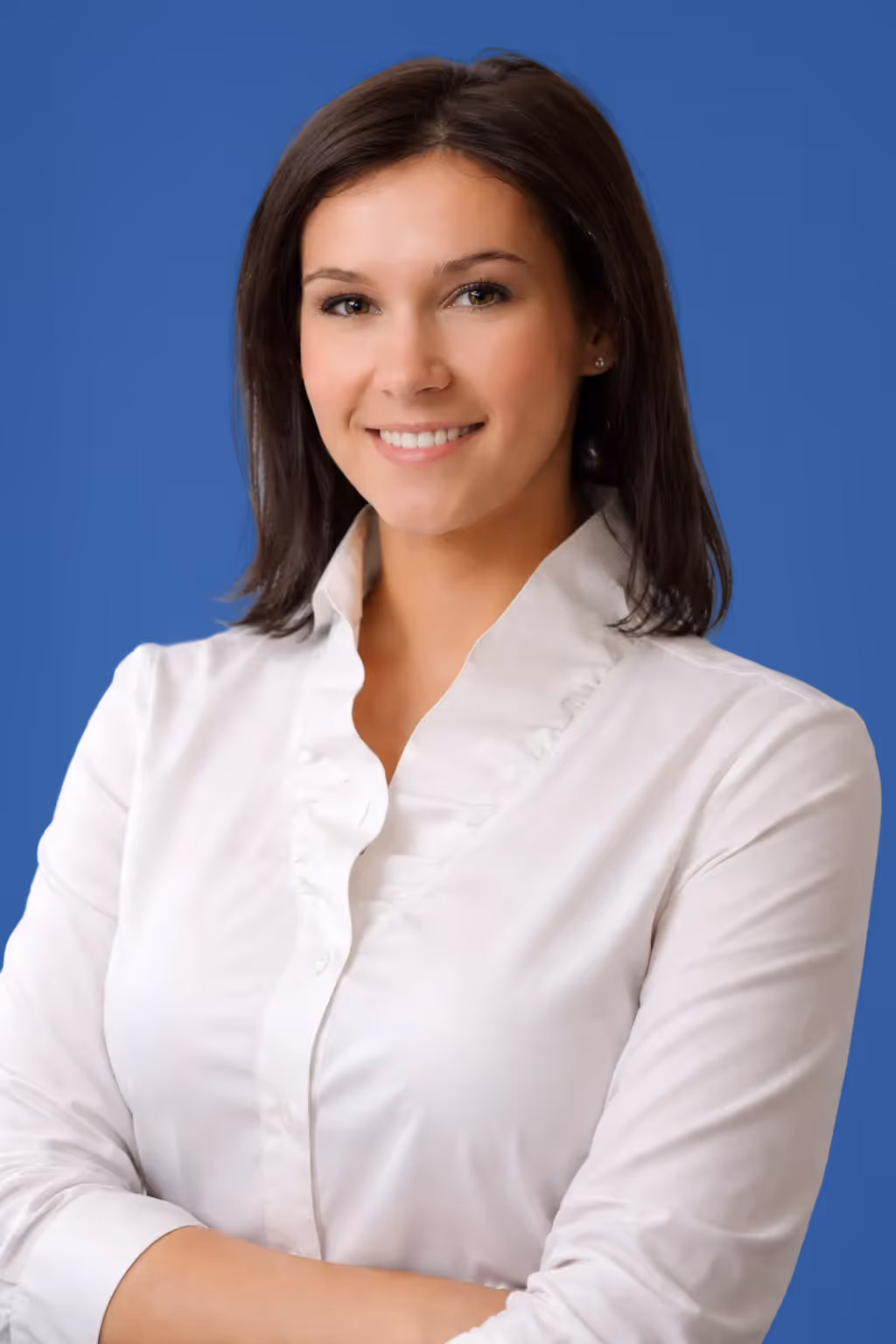 Mosolygó nő fehér blúzban kék háttér előtt, keresztbe font karokkal.