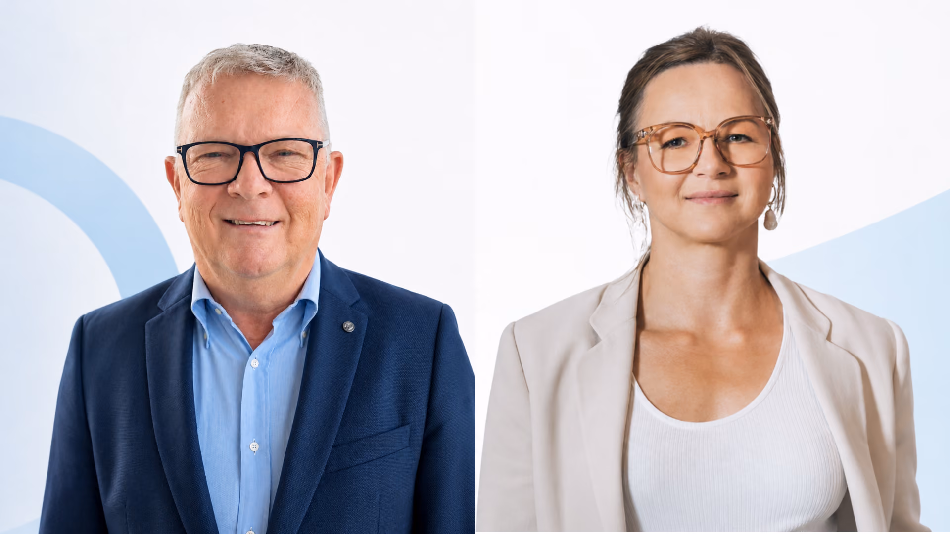 Eine Frau mit Brille und hellbeiger Jacke lächelt, während ein Mann mit kariertem Hemd und Brille gestikuliert und spricht.