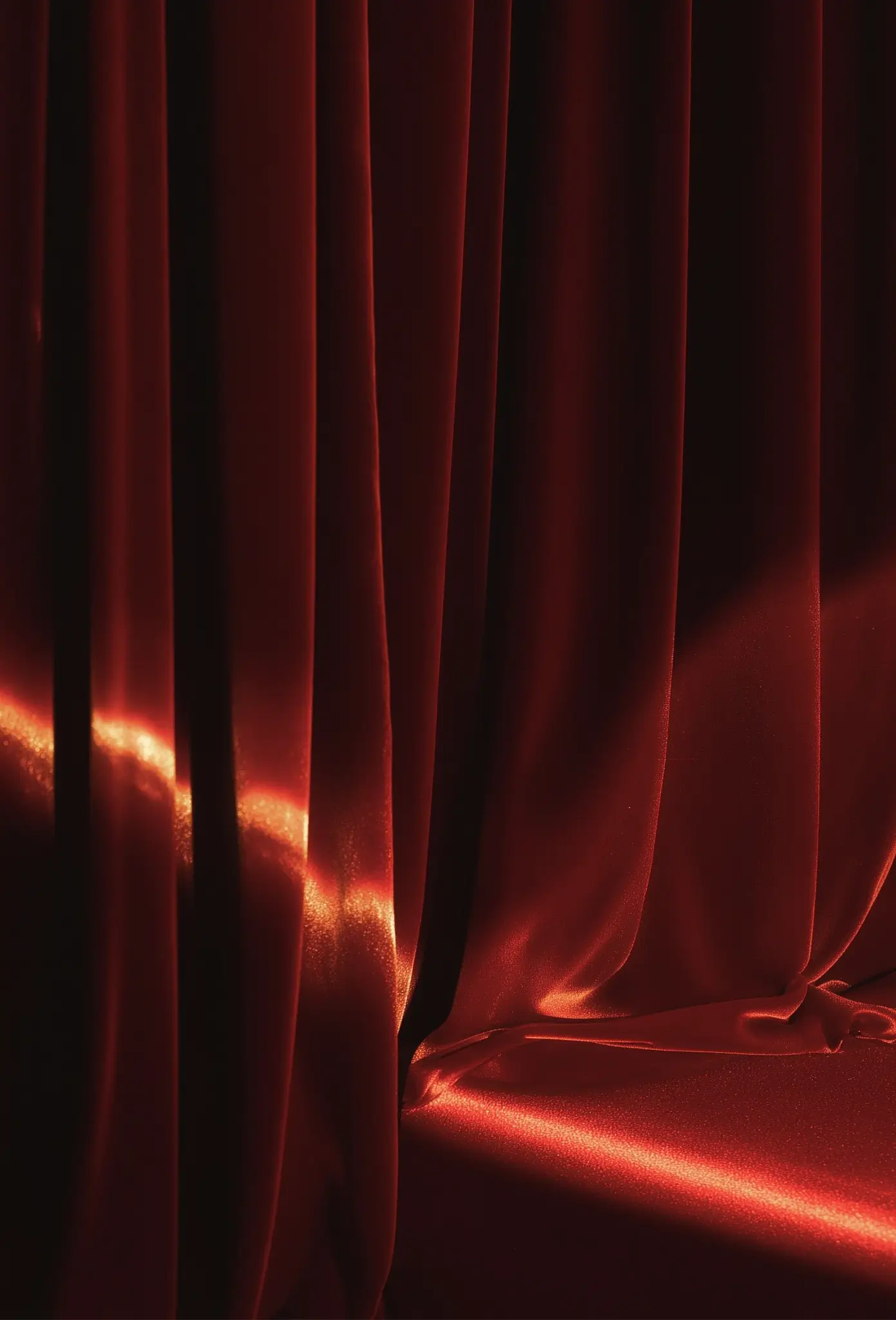 Tela roja drapeada con pliegues profundos y acabado satinado, imagen abstracta que evoca lujo y sofisticación.