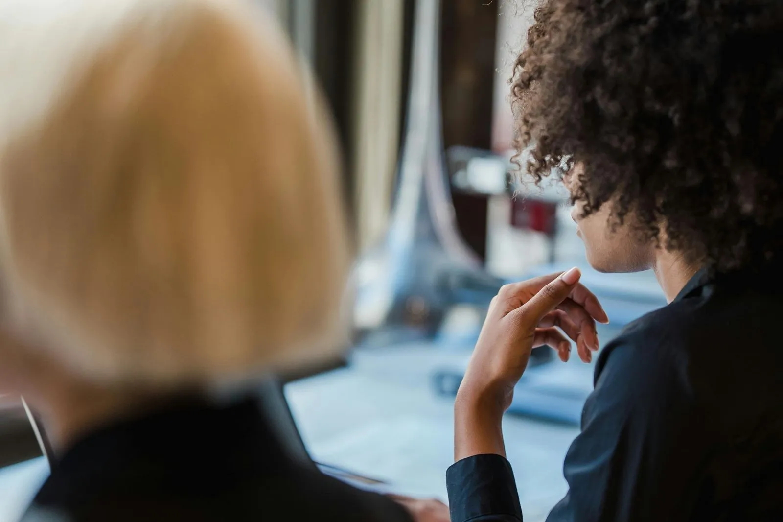 Two people in a conversation, one with curly hair gesturing with their hand.