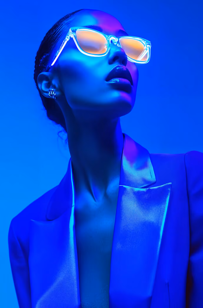 Person wearing futuristic virtual reality headset with glowing blue light in dark setting.
