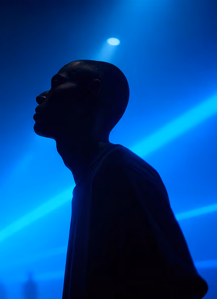 Silhouette of a person looking upward against a vibrant background with blue diagonal light beams.