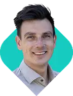 Jonge man met donker haar en lichte huid glimlacht terwijl hij een lichtgrijs overhemd draagt.