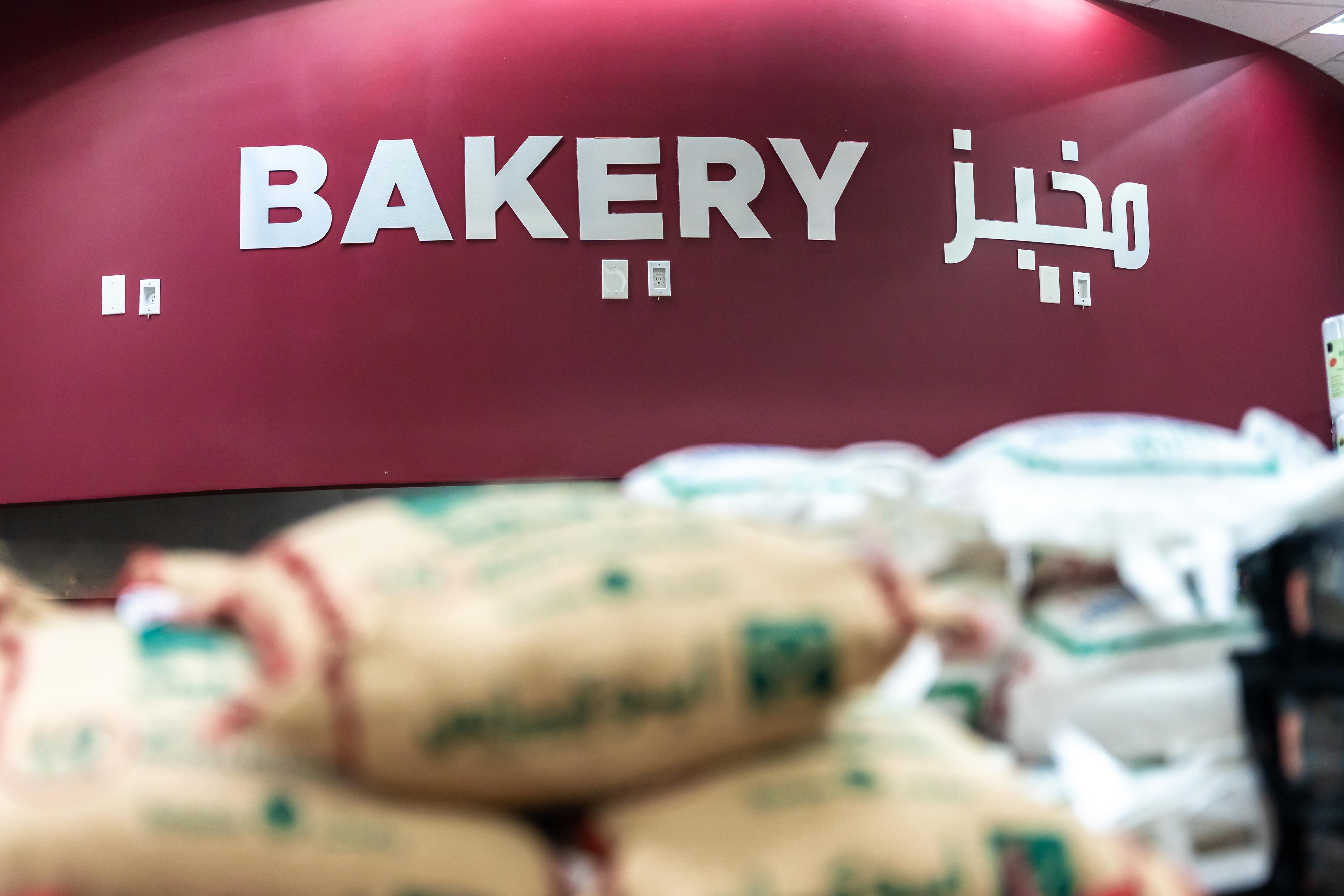 Assorted fresh baked breads including loafs and buns arranged on a flour-dusted dark surface.