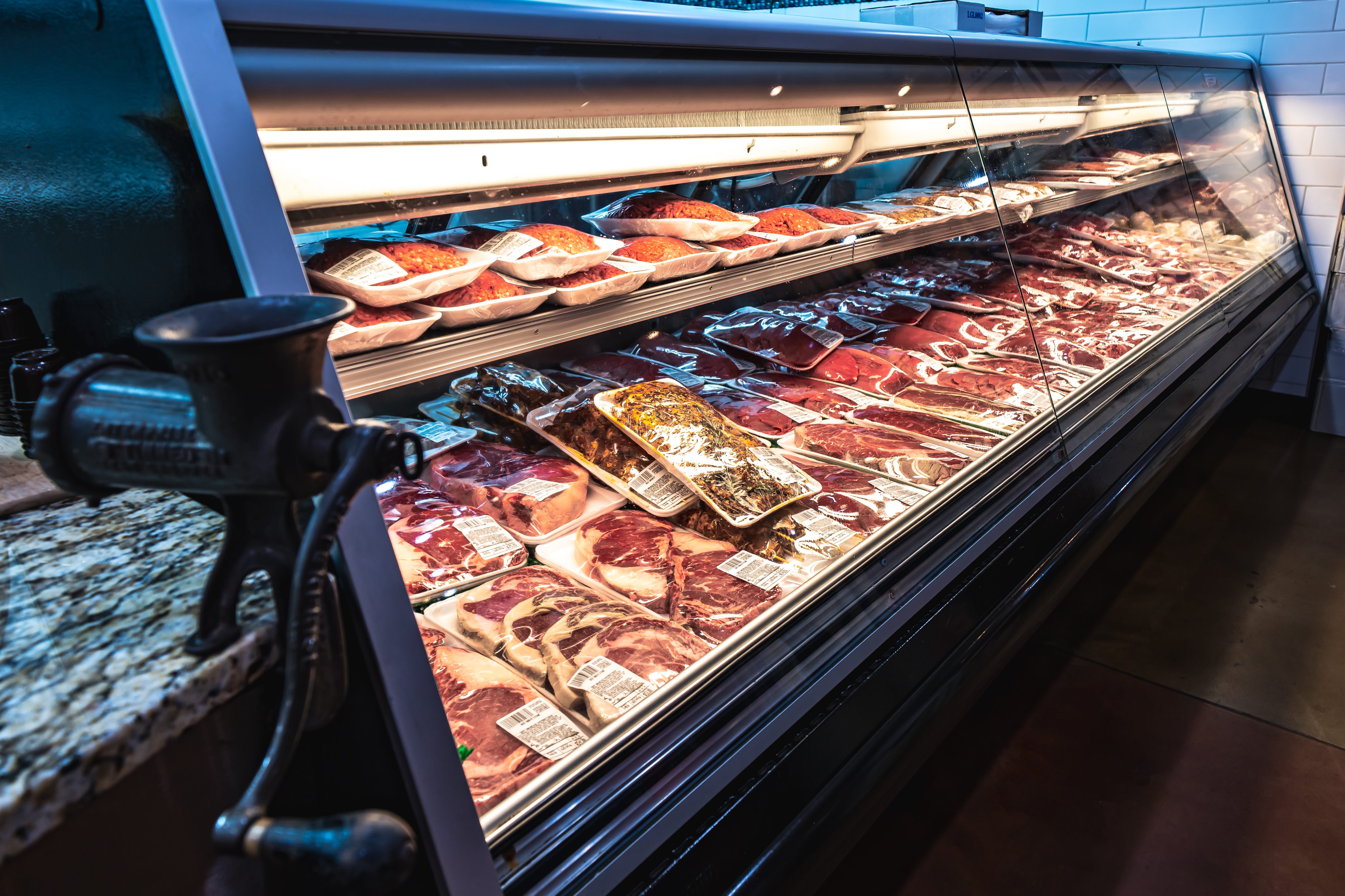 Refrigerated meat display case filled with packaged cuts of beef in a butcher shop.