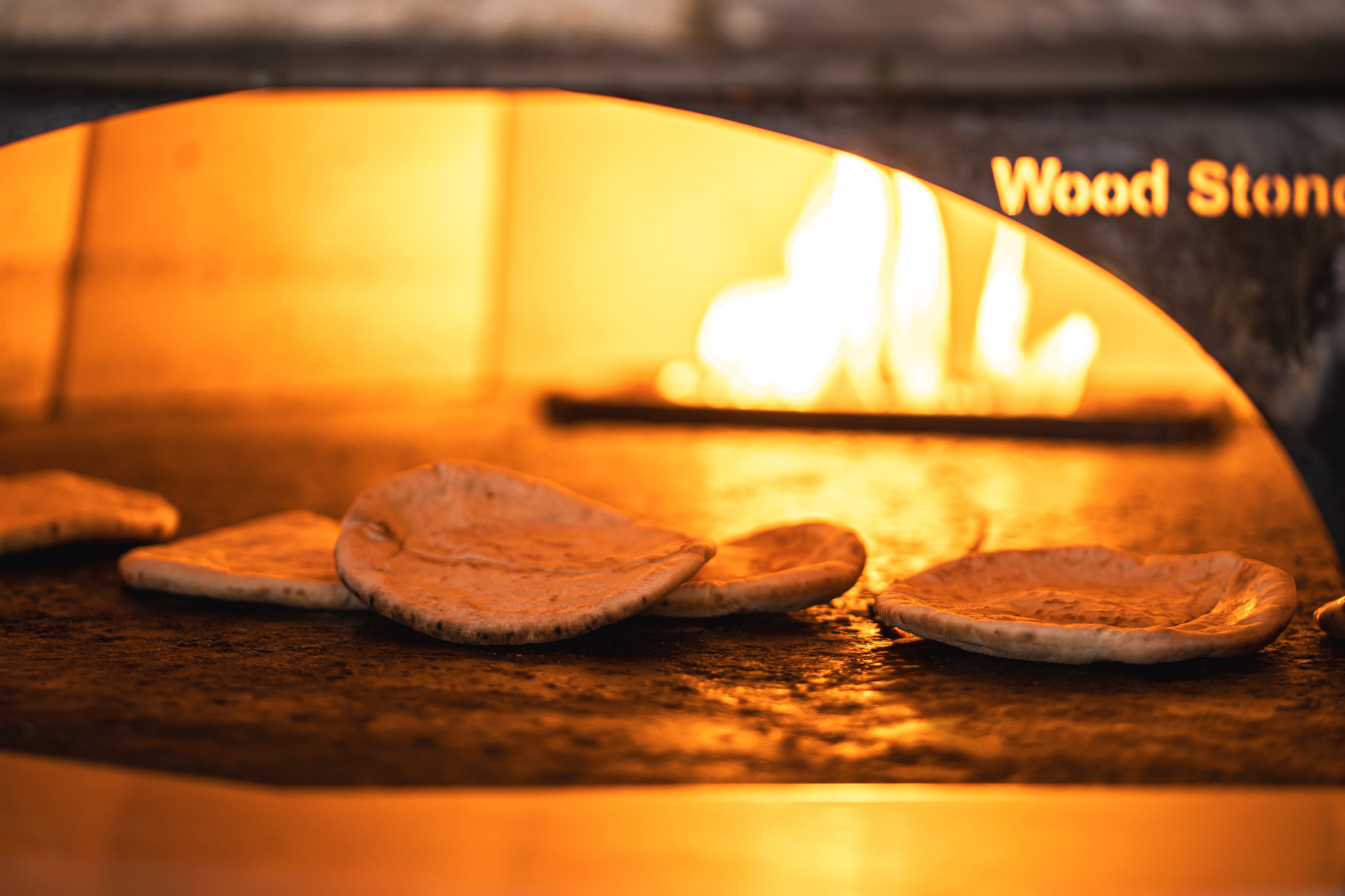 Wall with large white letters spelling 'BAKERY' in English and Arabic on a maroon background, with blurred stacked bags in the foreground.