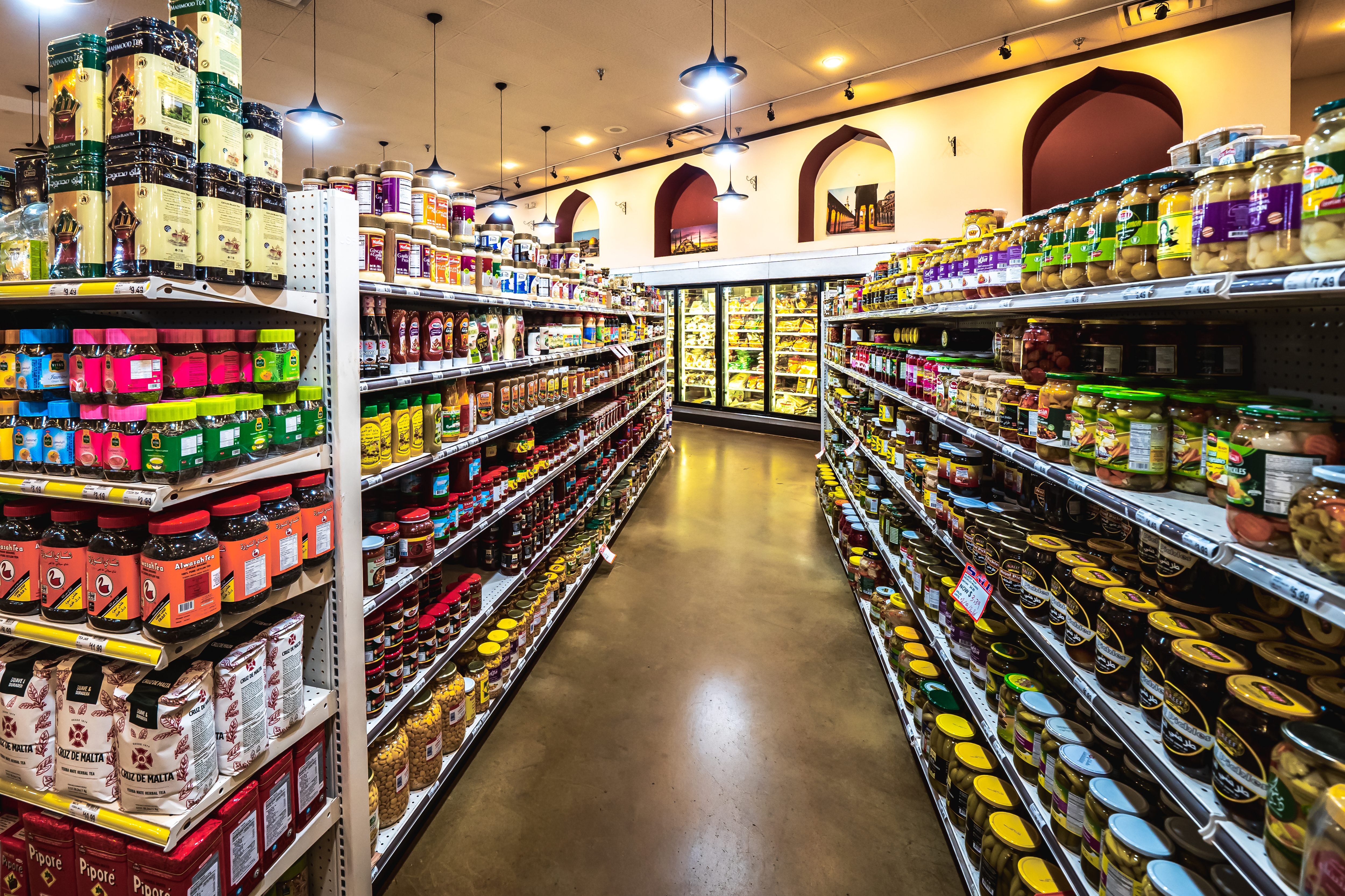 Exterior of Dukkan's International Market storefront at sunset with parked cars and shopping carts outside.