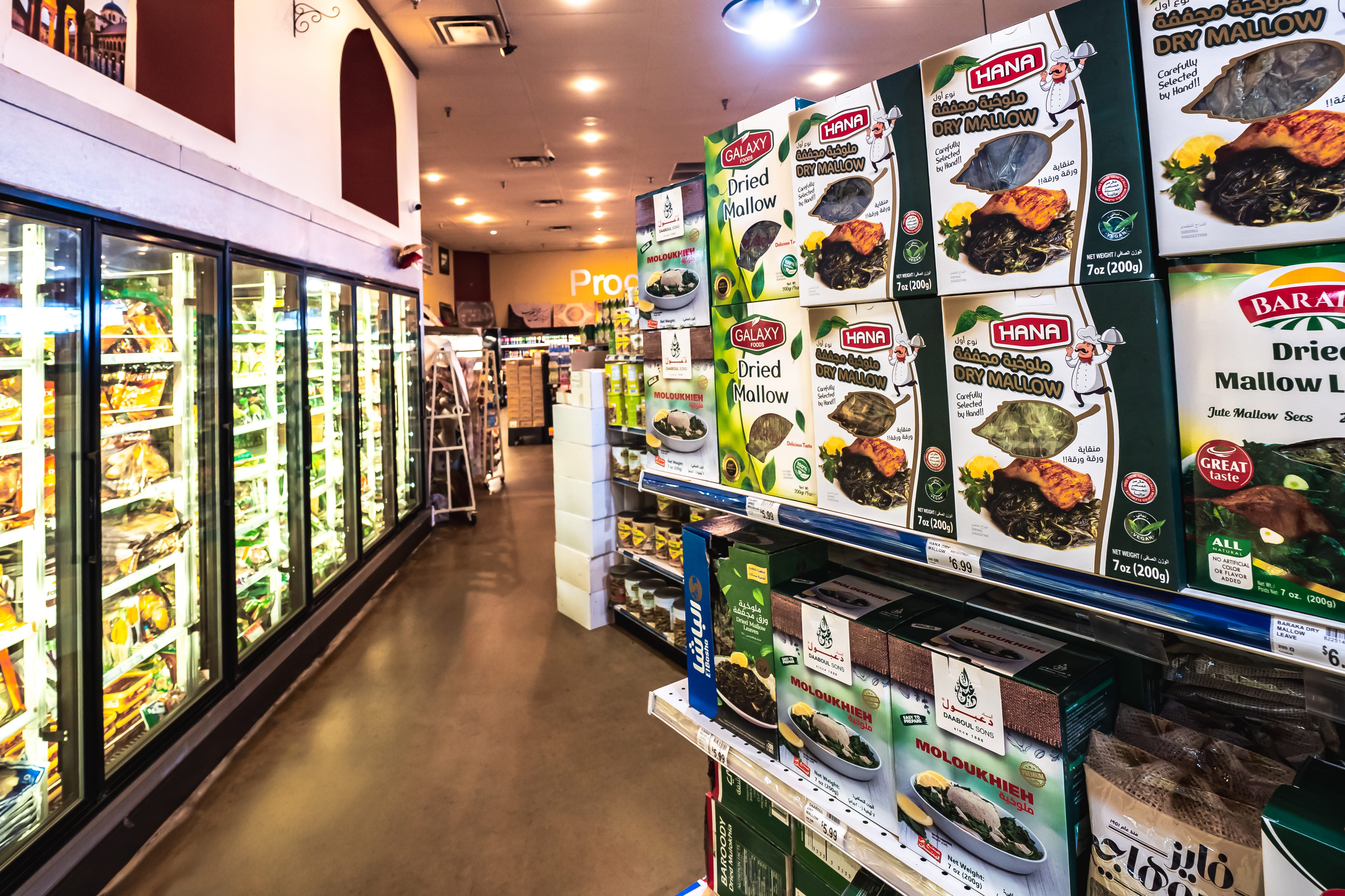 Grocery store aisle with shelves stocked with boxes of dried mallow and refrigerated cases on the left.