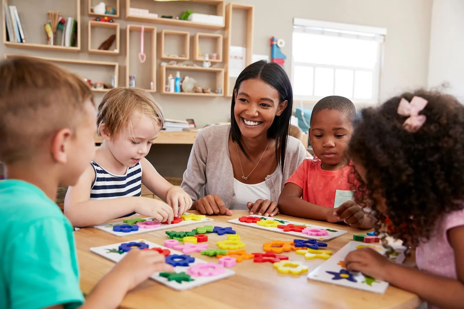 A woman is playing with children at a table.