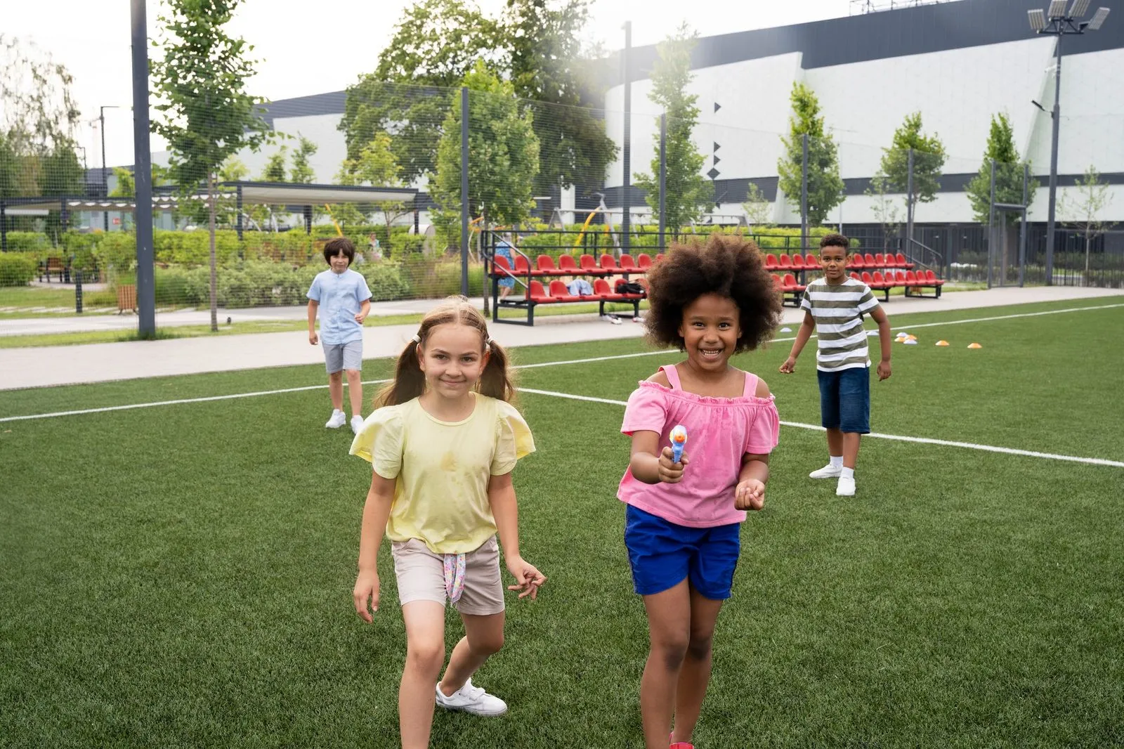 Two young girls walking across a grass covered field.