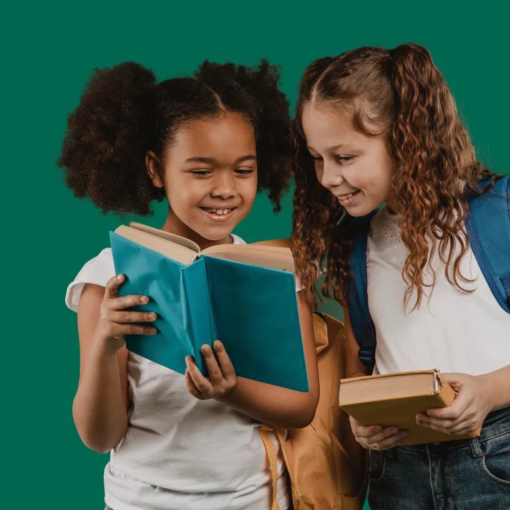 Two young girls are reading a book together.