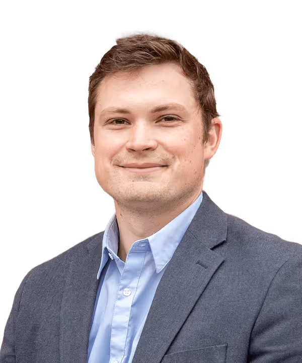 Smiling white man with short brown hair wearing a blue shirt and dark blazer.