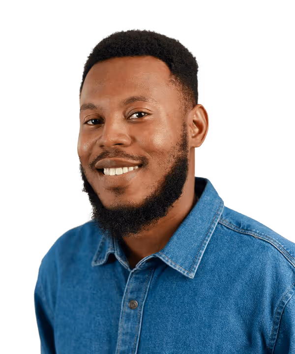 Smiling black man with short curly hair and beard wearing a blue denim shirt.