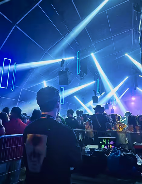 Personne debout devant une foule dans une salle avec des projecteurs bleus et blancs illuminant la scène d'un concert ou d'un événement.