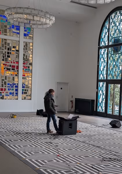 une personne dans une salle avec des vitraux deux enceintes placées au sol