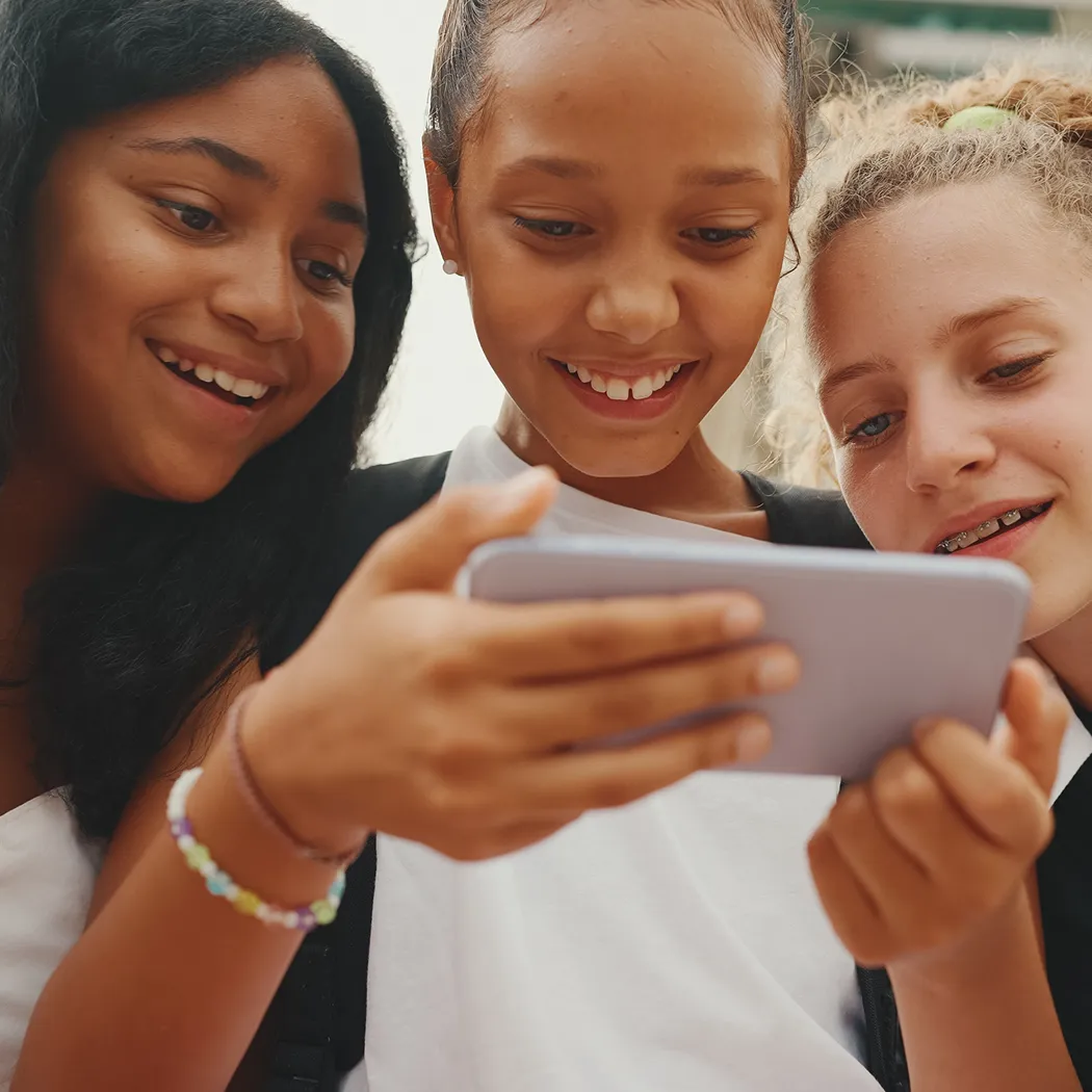 Kids exploring learn-to-earn app for kids on smartphone outdoors.