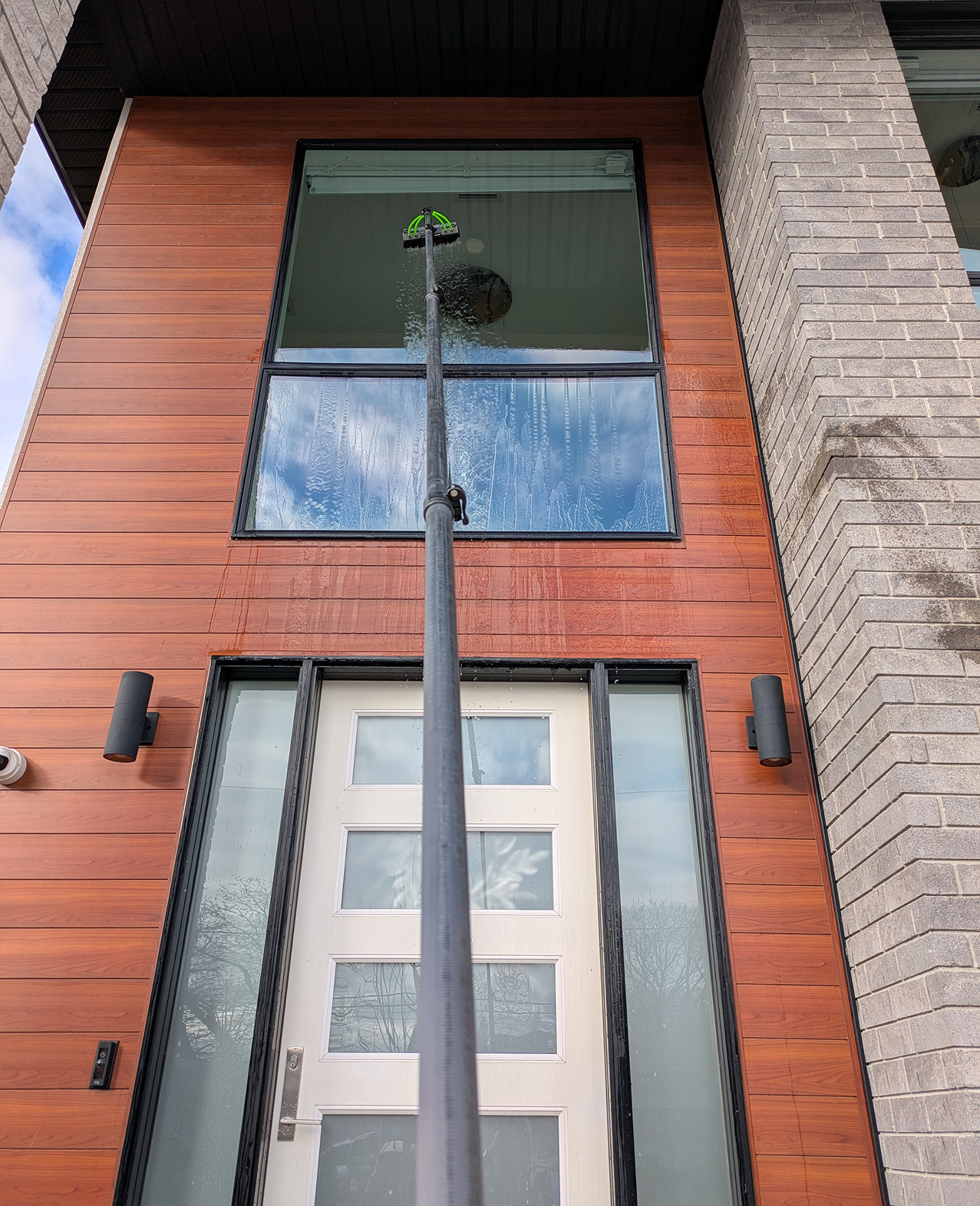 A large modern home with windows that are being cleaned streak-free.