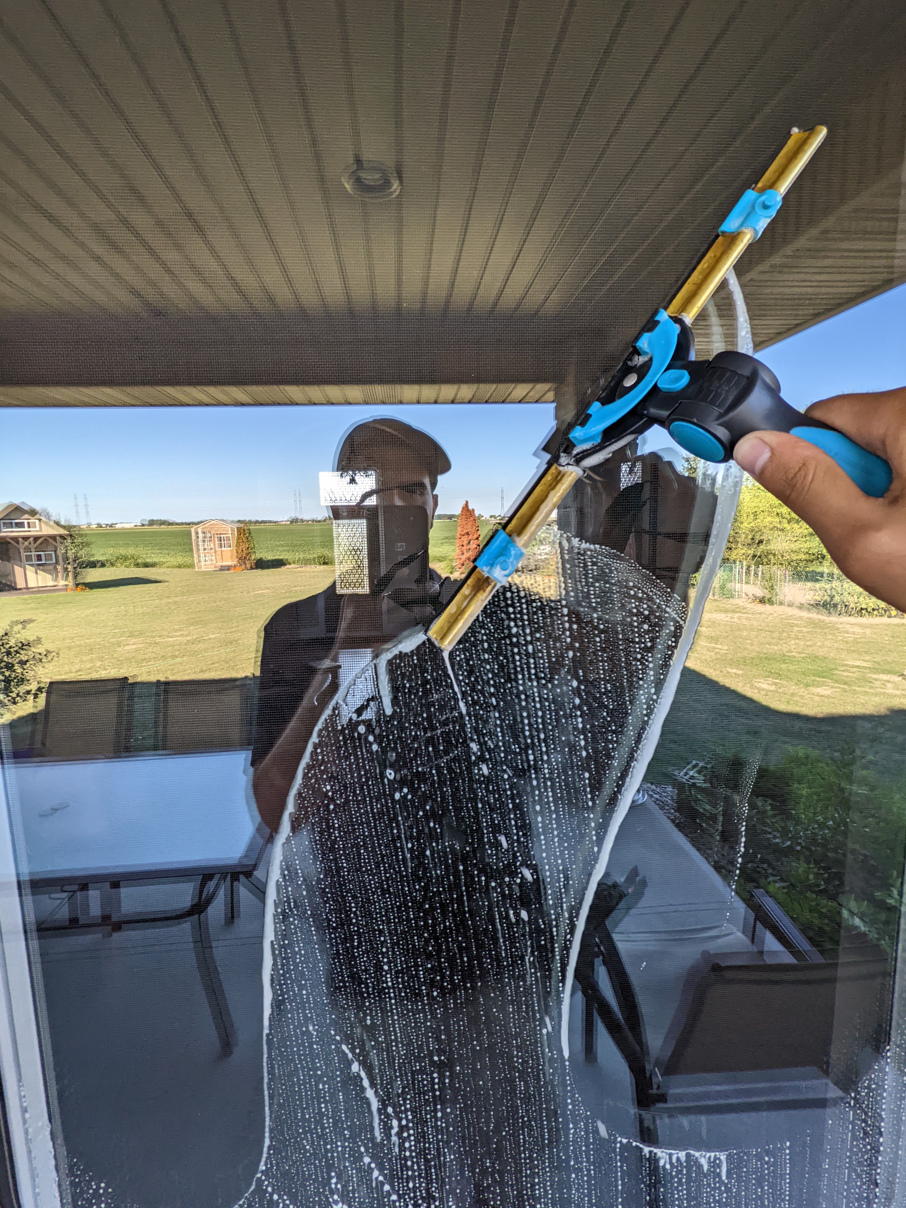 Window washer using a squeegee on a large glass pane.