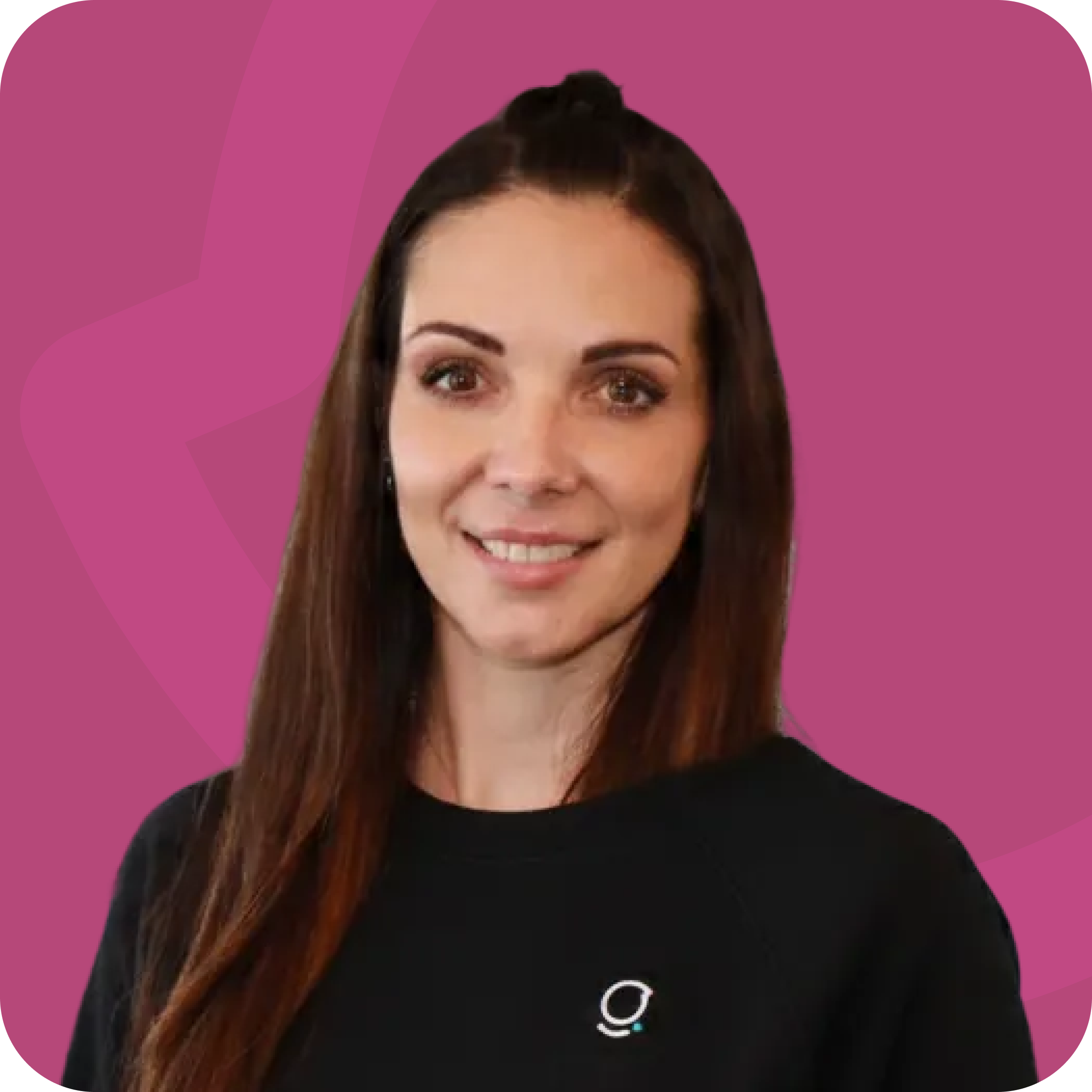 Smiling woman with long brown hair wearing a black shirt with a small white logo on a maroon background.