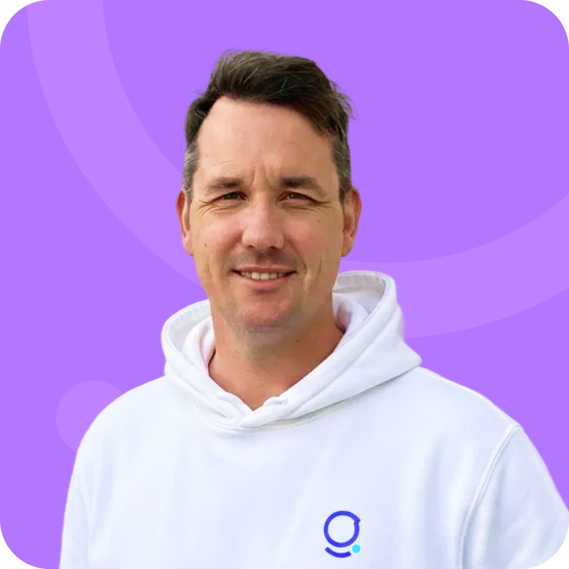 Man with short dark hair wearing a white hoodie with a blue circular logo on a purple background.