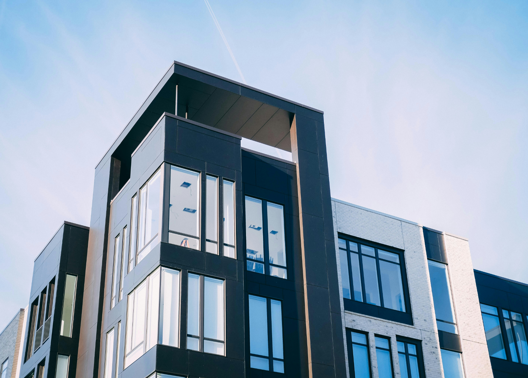 Modern multi-story building with large windows and a distinctive black and white exterior under a clear sky.