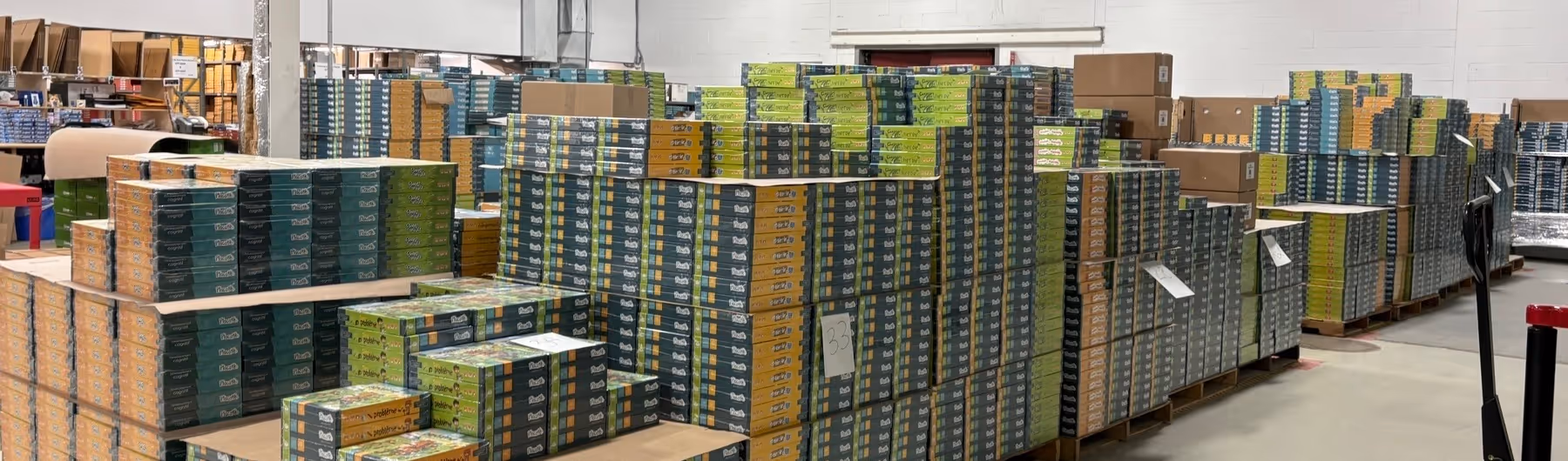 Grande quantité de boîtes empilées sur des palettes dans un entrepôt bien éclairé.