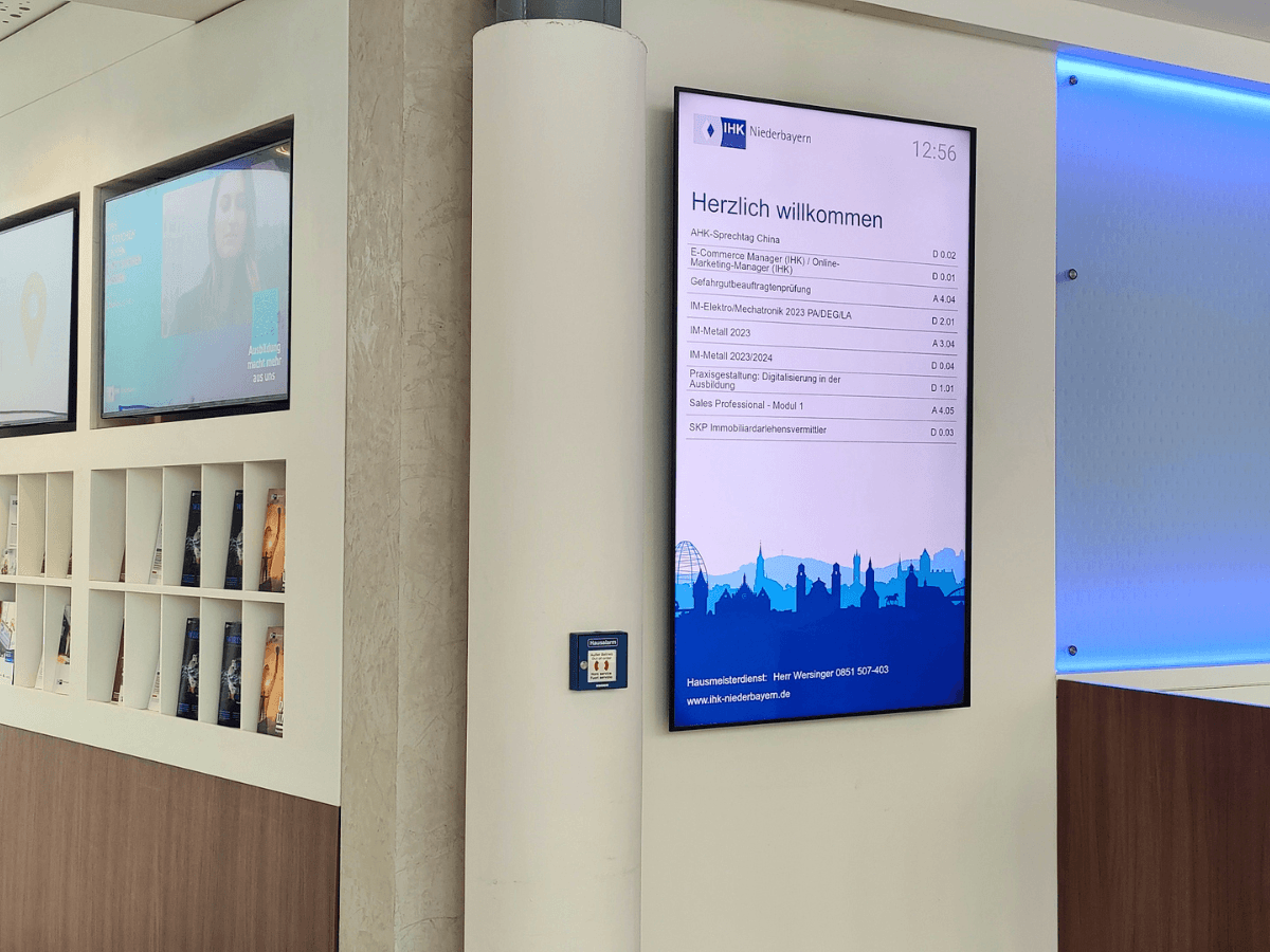 The digital signage welcome screen at the IHK Lower Bavaria displays events, the time, and room information in the entrance area.