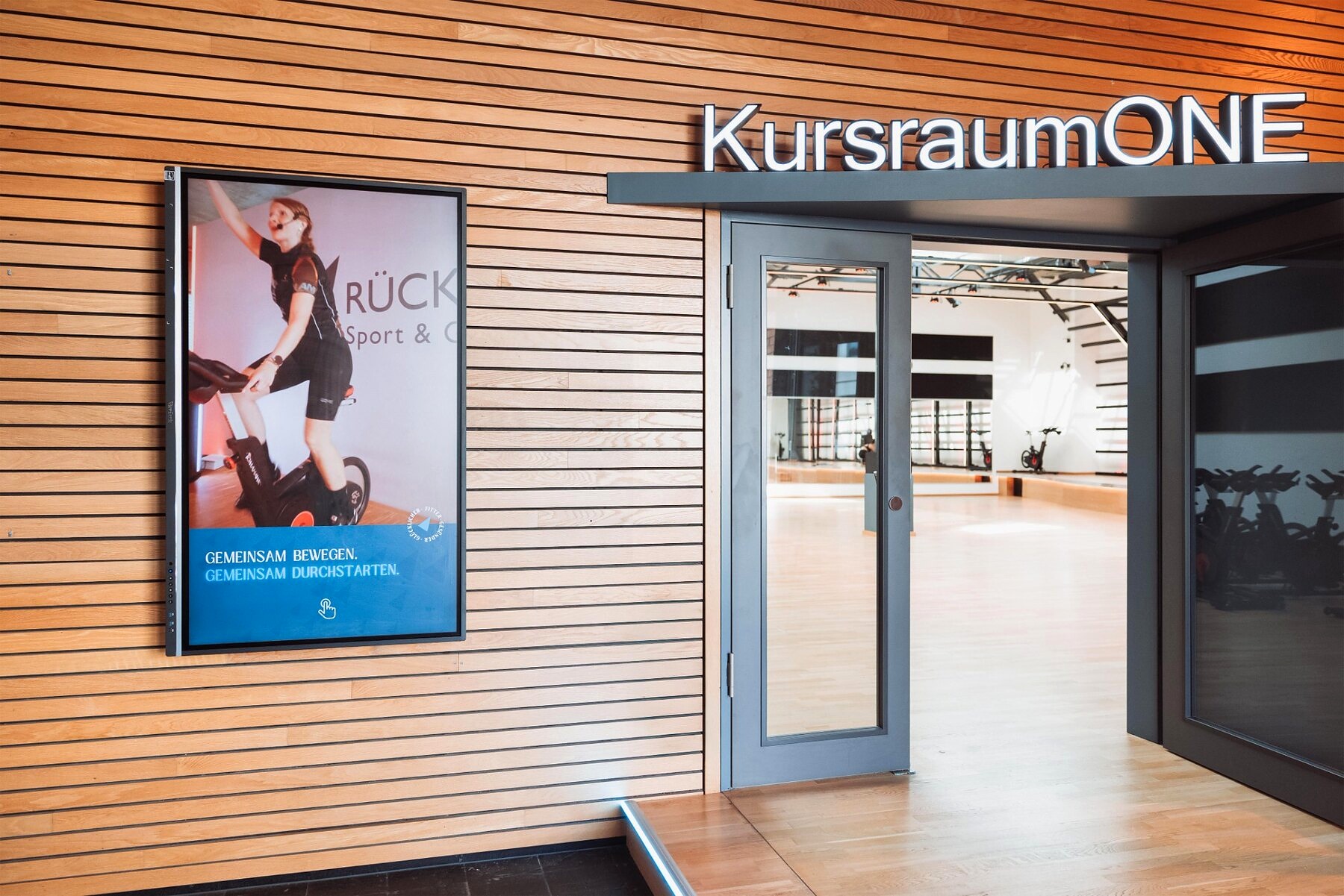 Digital Signage display at the Alter Zollhof studio shows current fitness content outside the course room