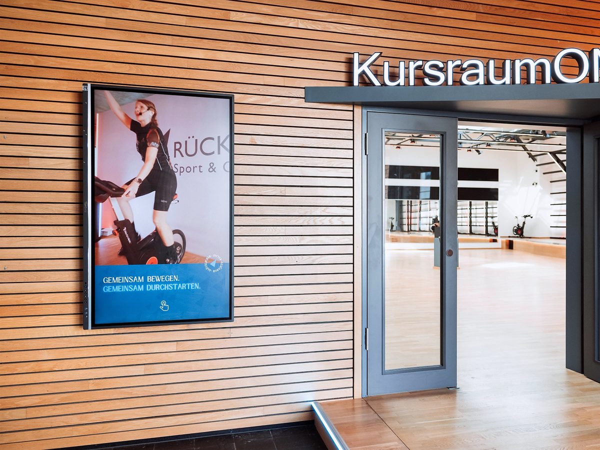 Interaktives Digital Signage Display der Rückgrat Gruppe am Eingang zum Kursraum Alter Zollhof zeigt aktuelle Fitnessinhalte