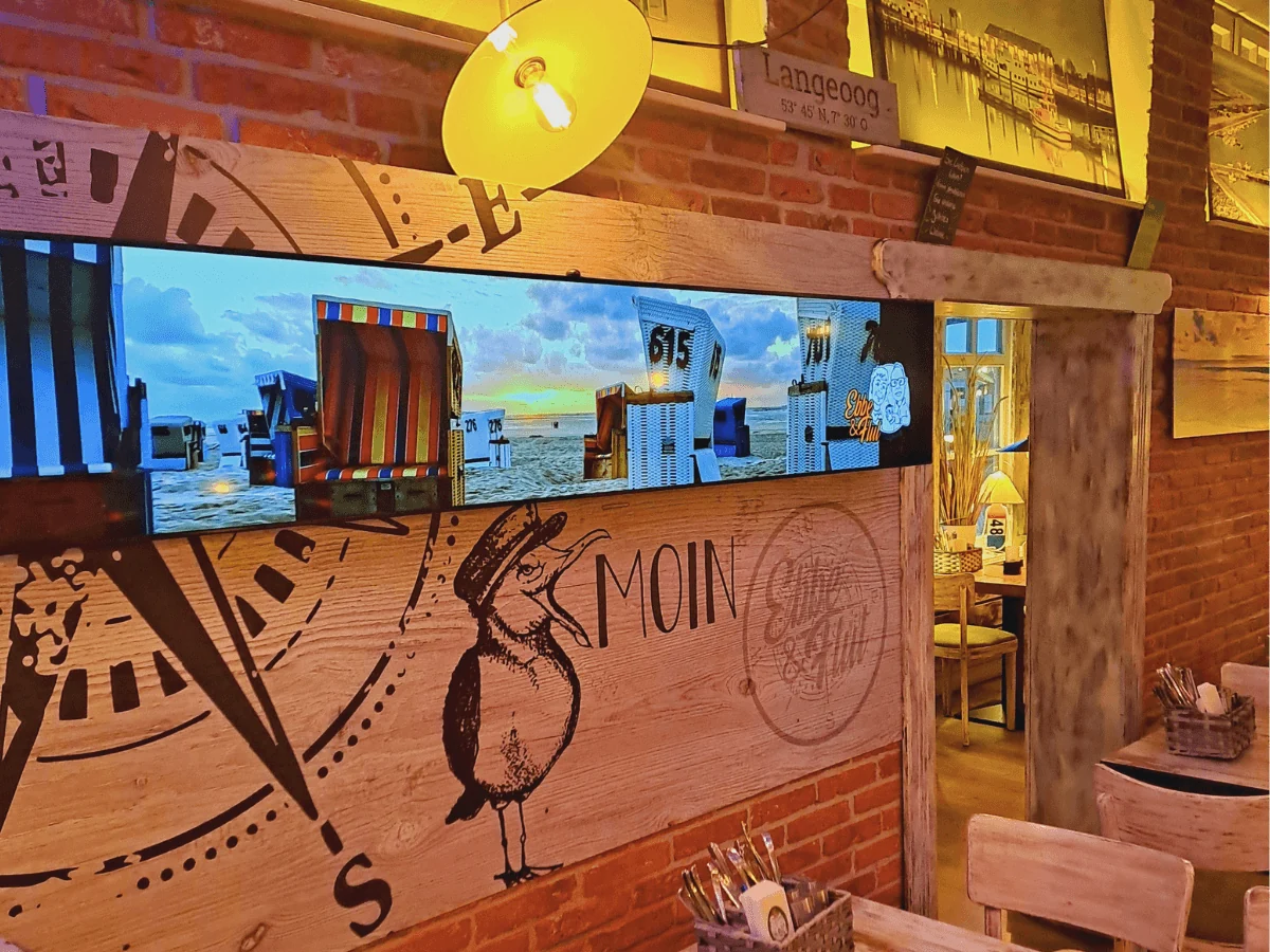 Breites Display mit Strandkorb-Motiv an der Backsteinwand im Restaurant EBBE & FLUT auf Langeoog