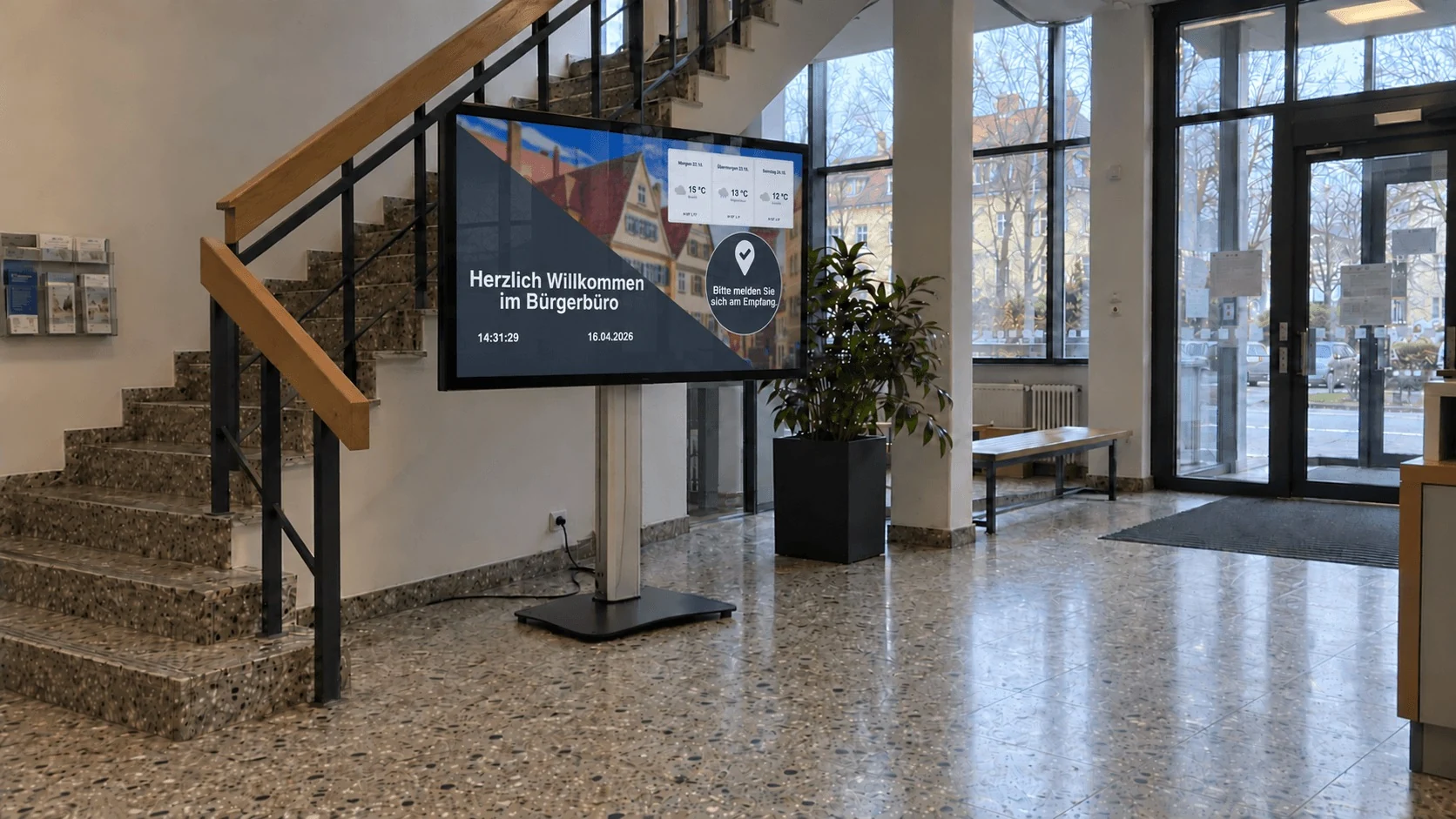 Illustratives Anwendungsszenario: Freistehendes Display im Bürgerbüro-Foyer mit Willkommensanzeige, Wetter und Hinweis zur Anmeldung am Empfang