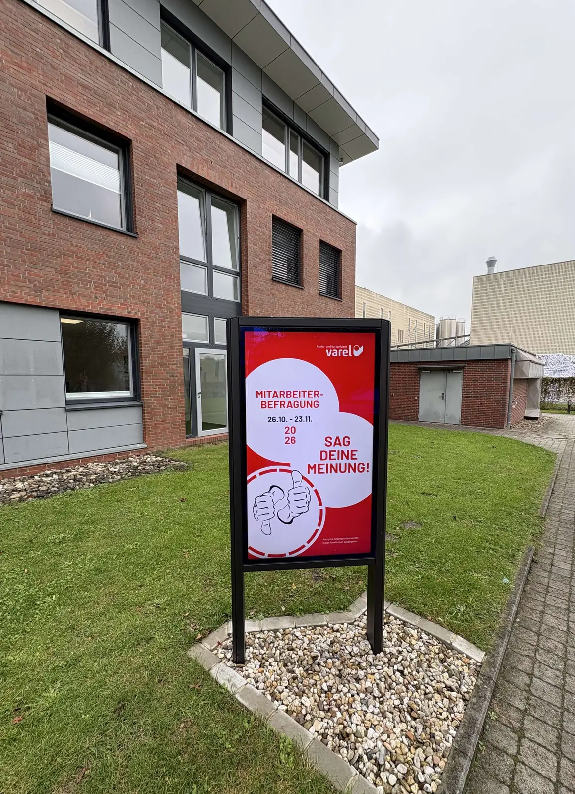 Hochformatdisplay vor dem Verwaltungsgebäude in Varel wirbt mit „Sag deine Meinung“ für die Mitarbeiterbefragung