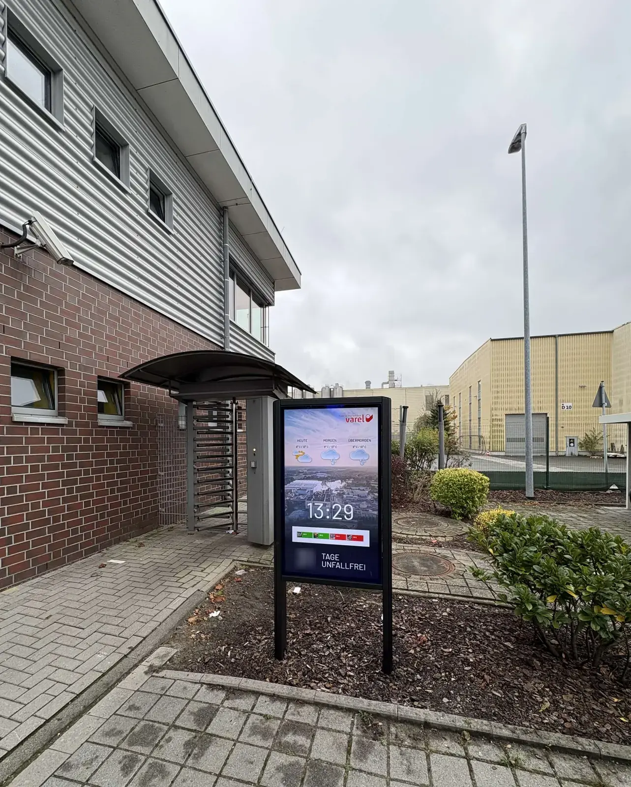 Outdoor-Infoboard am Drehkreuz der Papier- und Kartonfabrik Varel zeigt Wetter, Uhrzeit und unfallfreie Tage