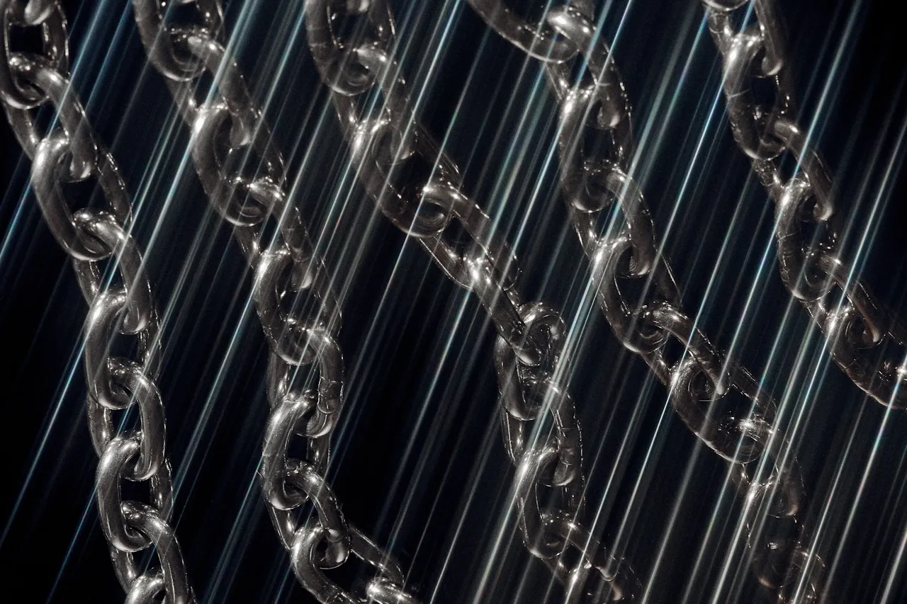 Close-up of several metal chains with diagonal light streaks creating a glowing effect.