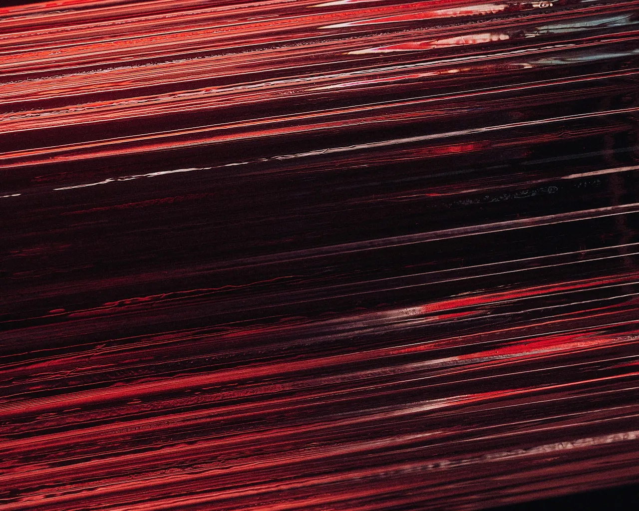 Close-up of dark red and black abstract flowing lines with glossy texture.