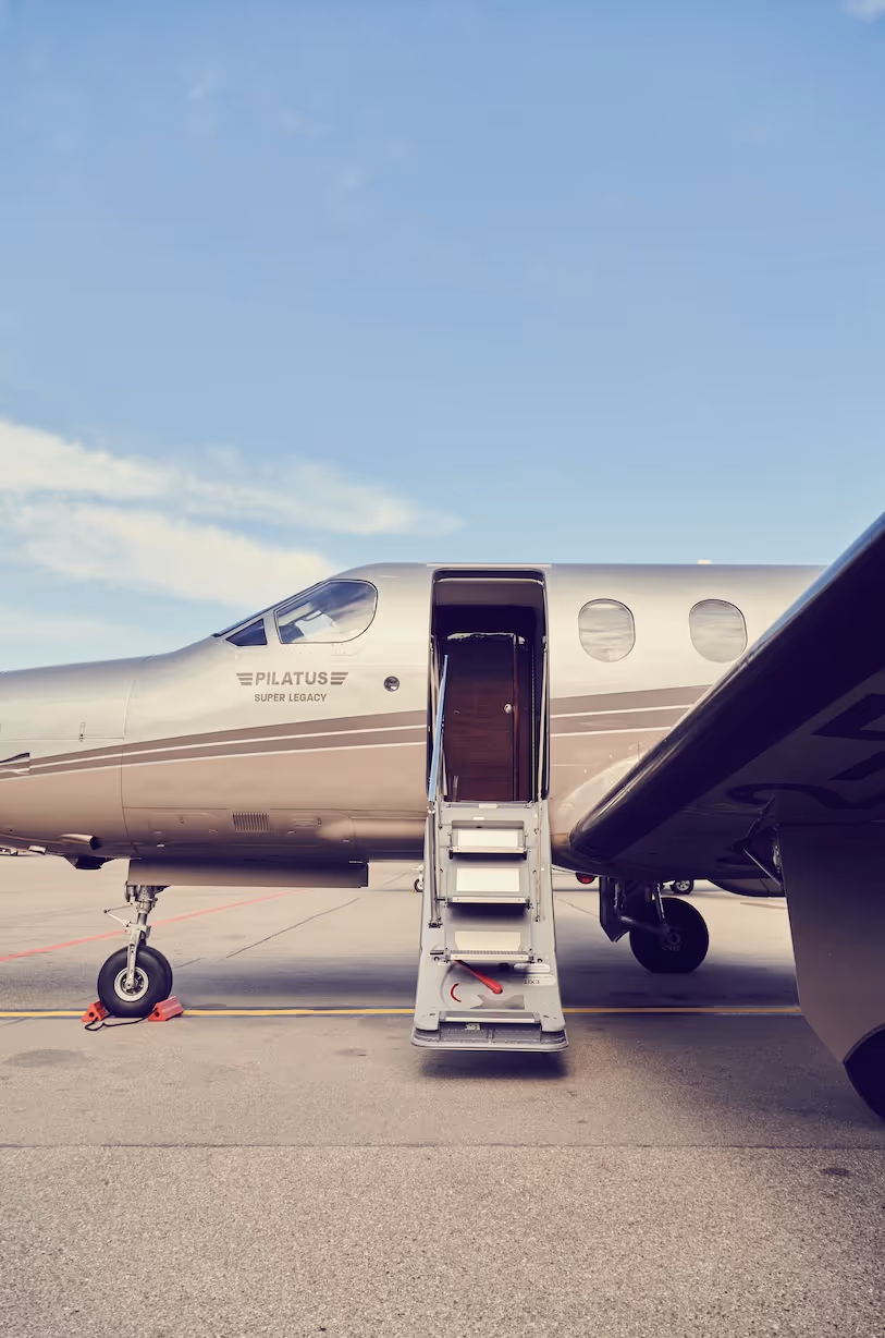 Pilatus Super Legacy aircraft with open cabin stairs on airport tarmac.