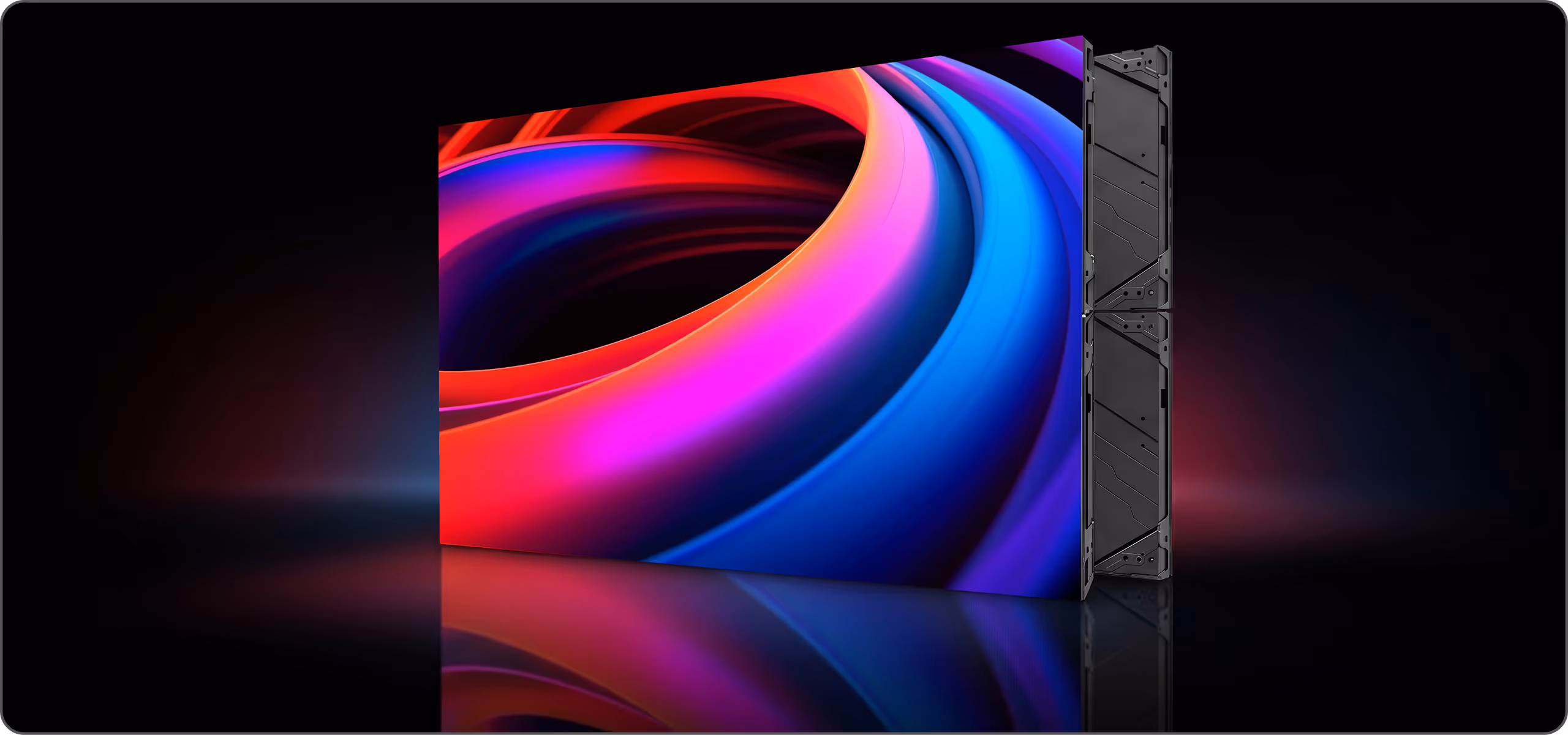 Large LED screen displaying a colorful abstract swirl pattern mounted on a black modular panel system against a dark background.