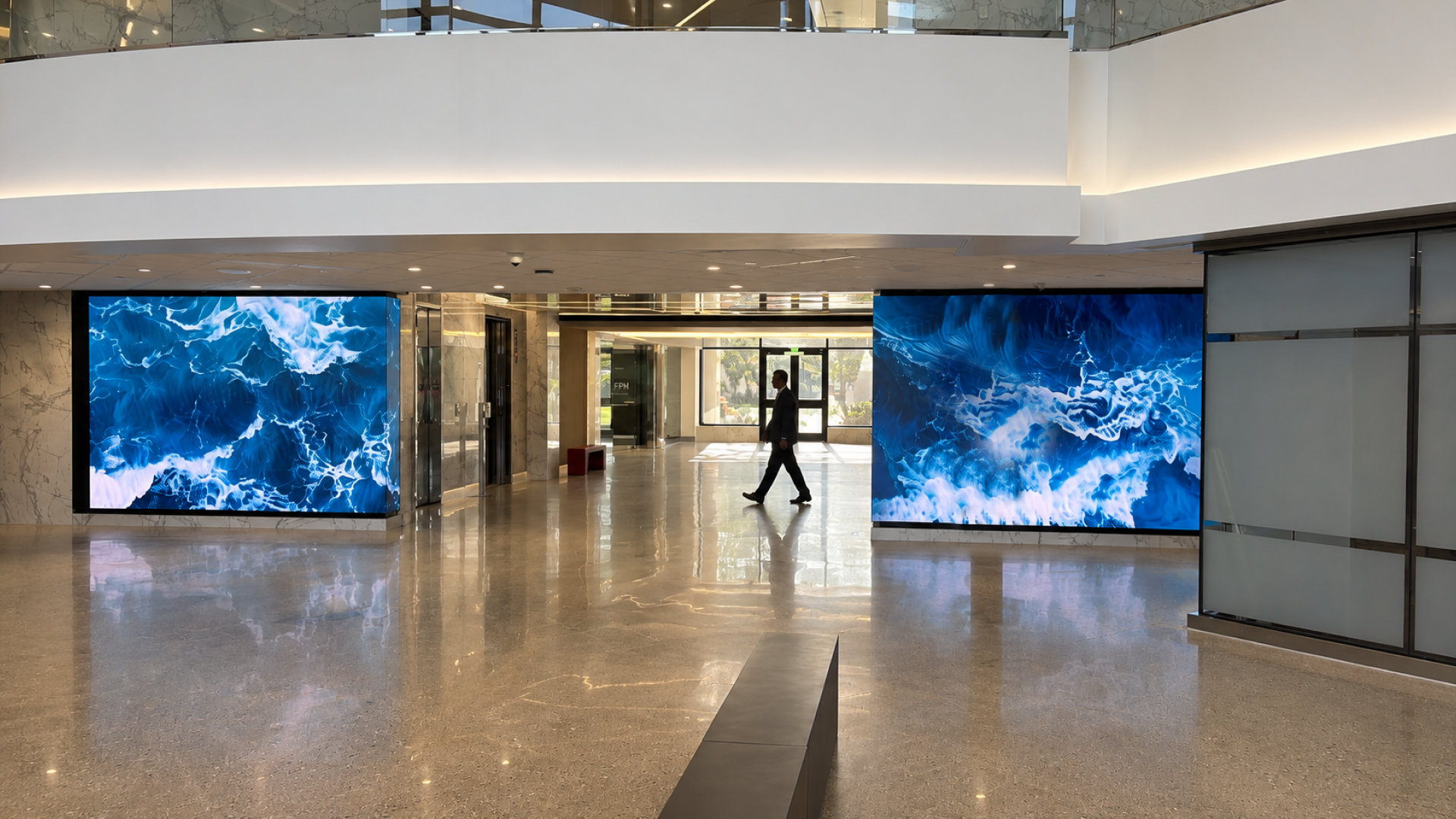 The result is a corridor that no longer feels like a transition between the entrance and the elevators. Synchronized digital content brings movement and visual energy to both sides of the space, complementing the marble and glass while giving visitors an experience that unfolds as they walk through it. What was once a functional passage is now a deliberate architectural moment, where content, technology, and material work together to transform the journey through the building. Two synchronized Vision X walls. Matching column displays. One corridor transformed by motion.