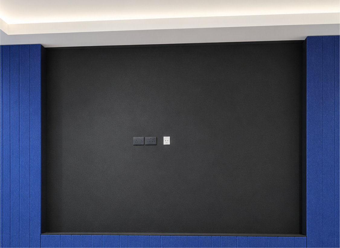iCapital's Singapore office, based in CapitaSpring, needed a breakout or gathering space with real visual presence, built around a dark accent wall framed by blue paneling and casual high-top seating.