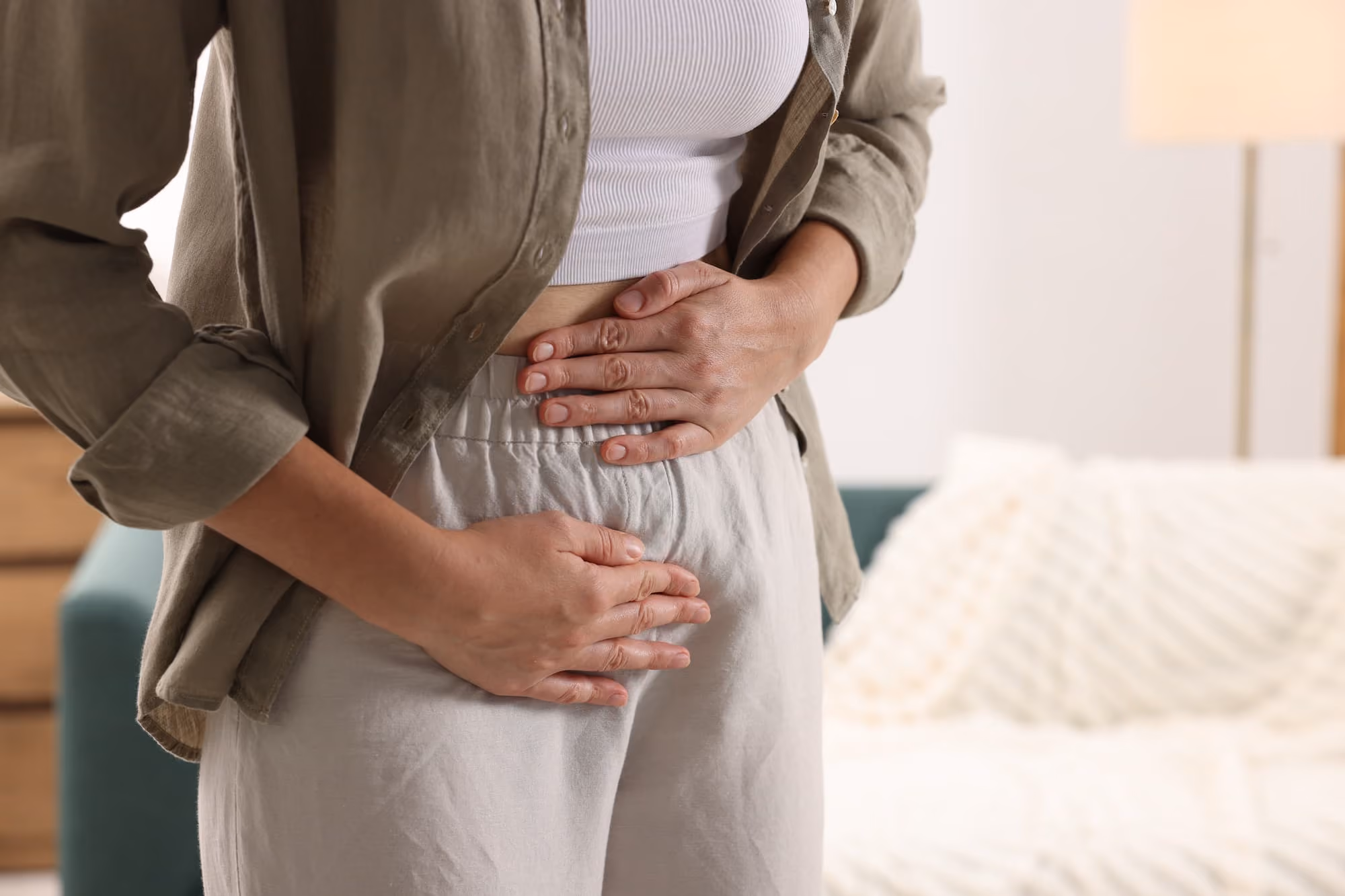 Woman clutching her lower abdomen, indicating abdominal discomfort or pain.