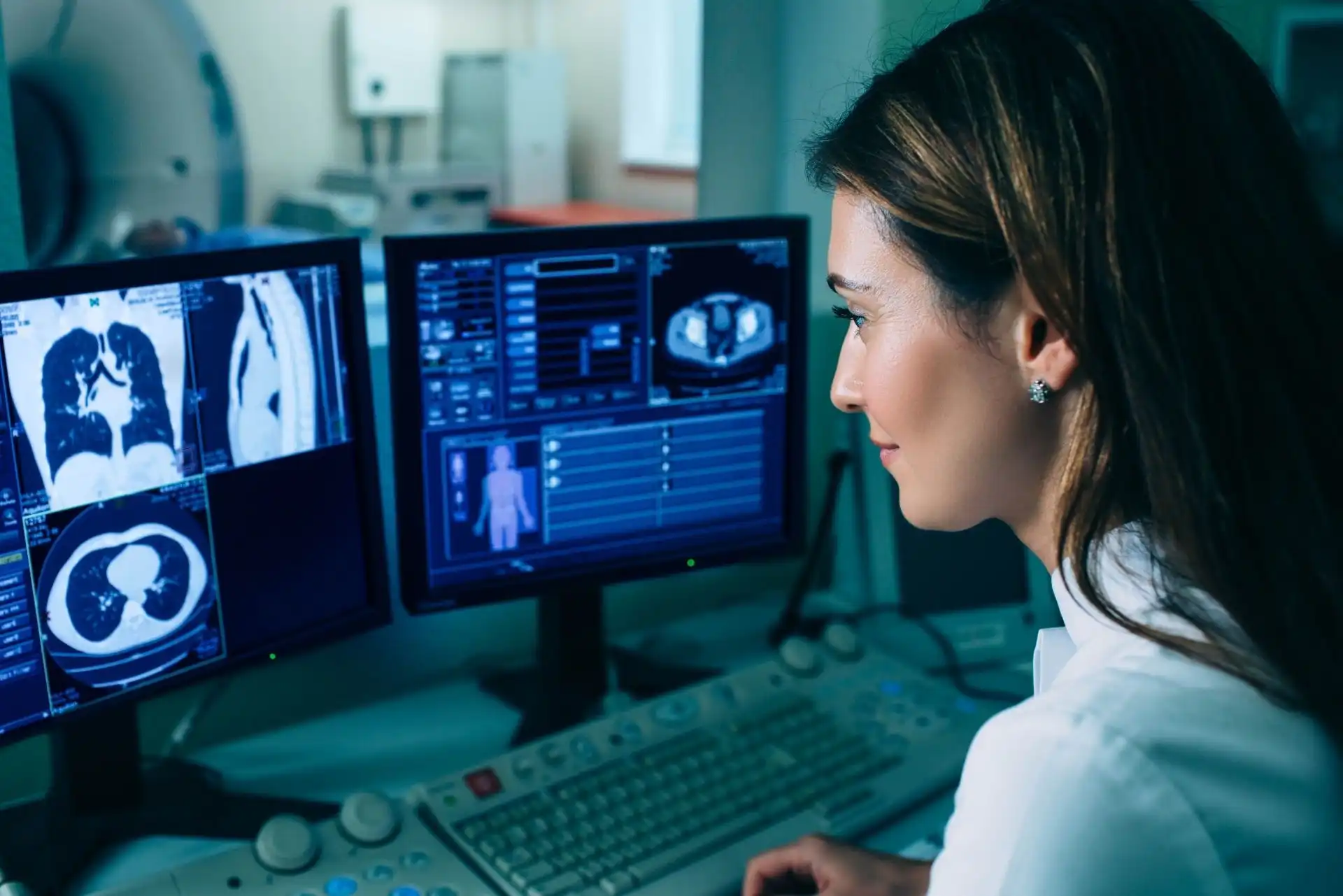 Medical professional analyzing diagnostic scan images on dual computer monitors in a clinical setting.