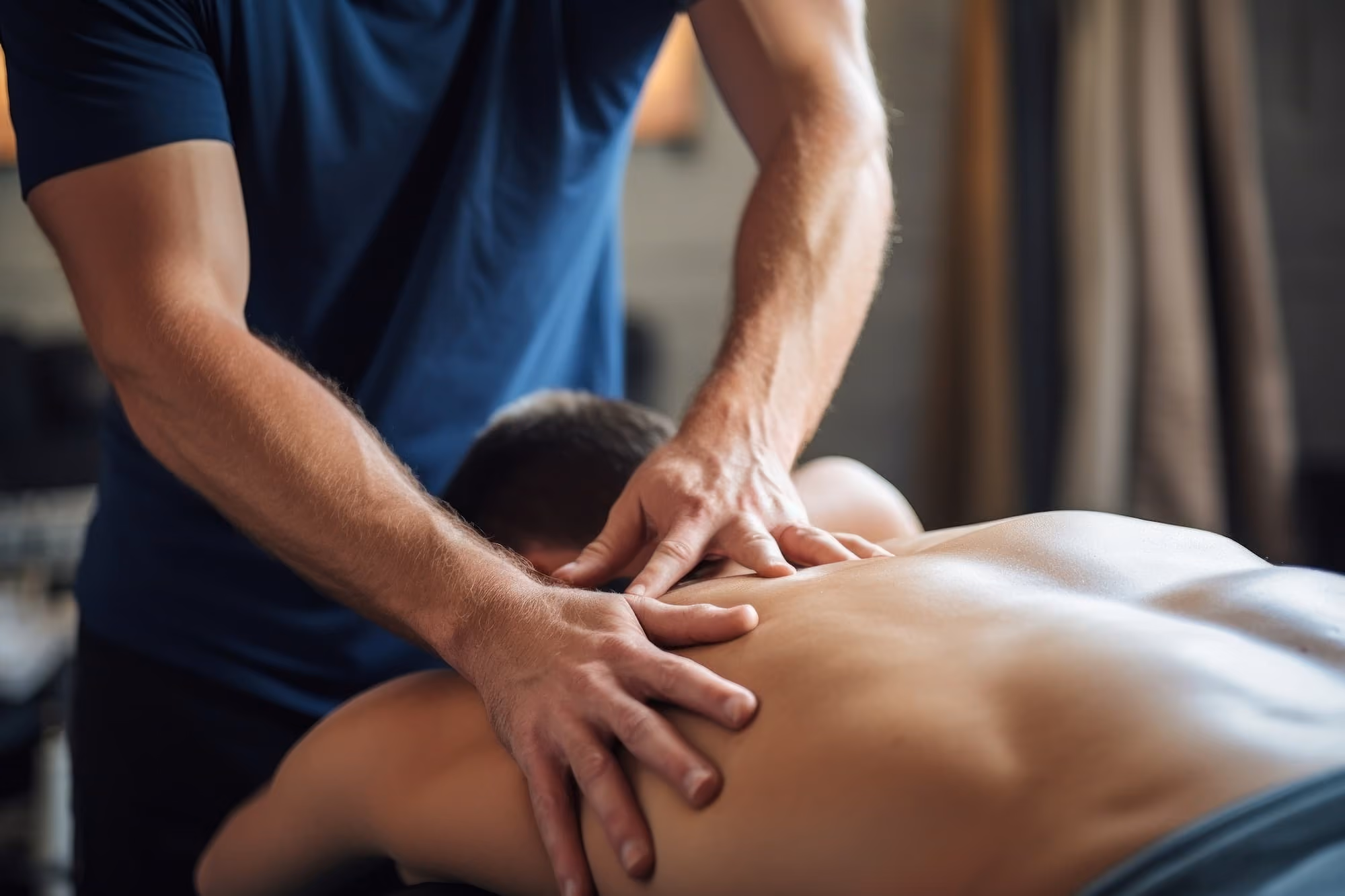 Therapist giving a back massage to a person lying face down.