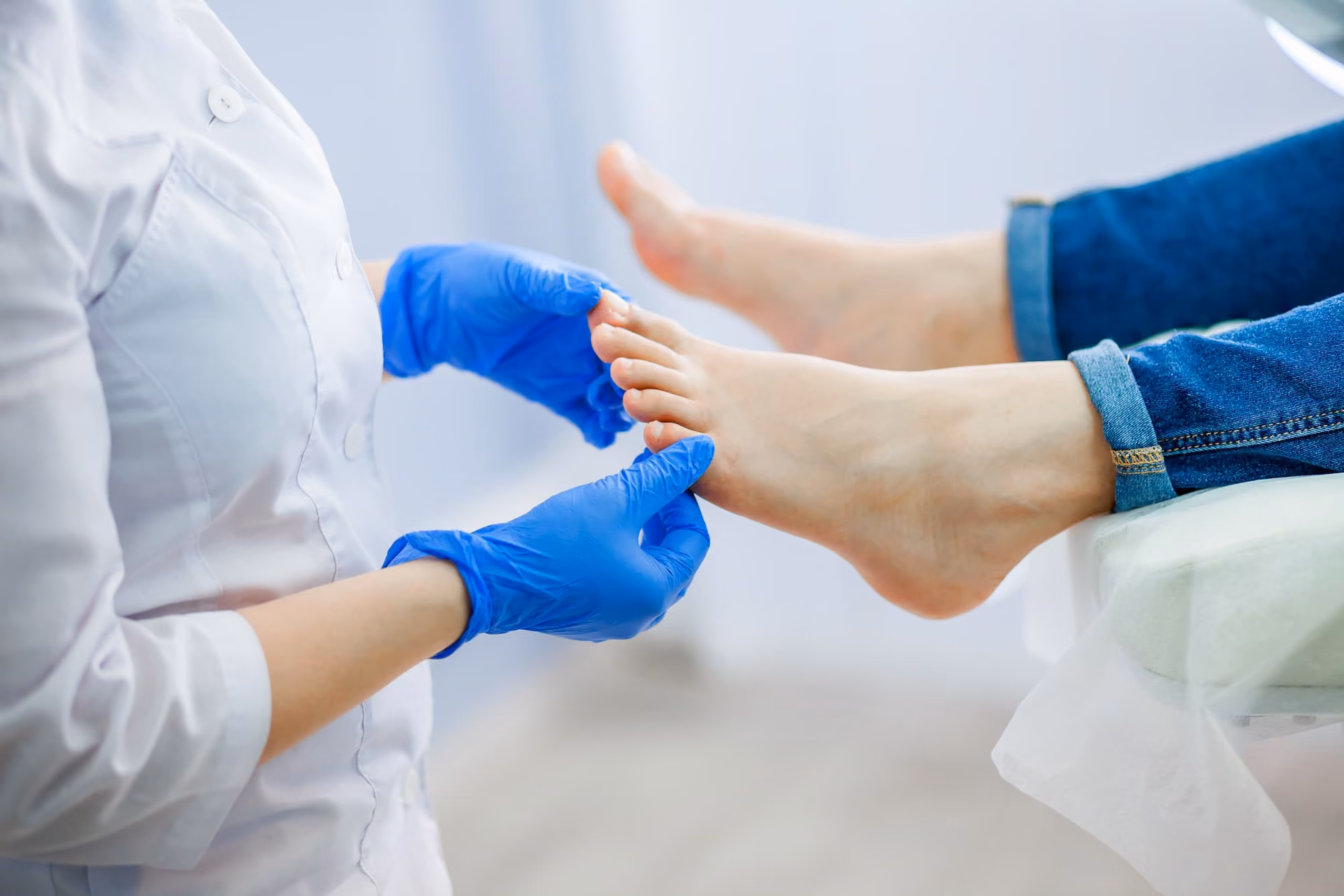 Healthcare professional wearing blue gloves examining a patient's foot.