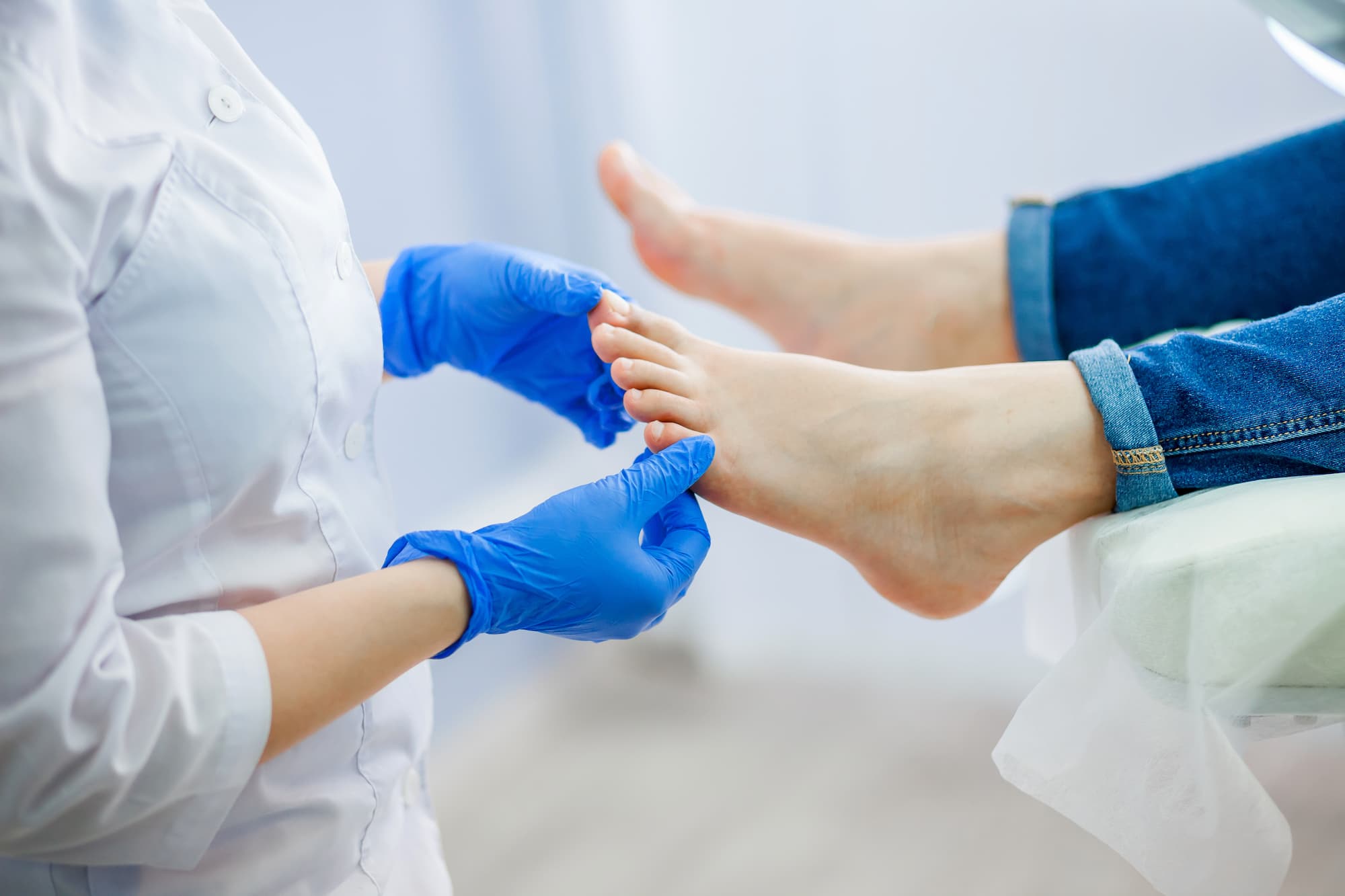 Healthcare professional wearing blue gloves examining a patient's foot.