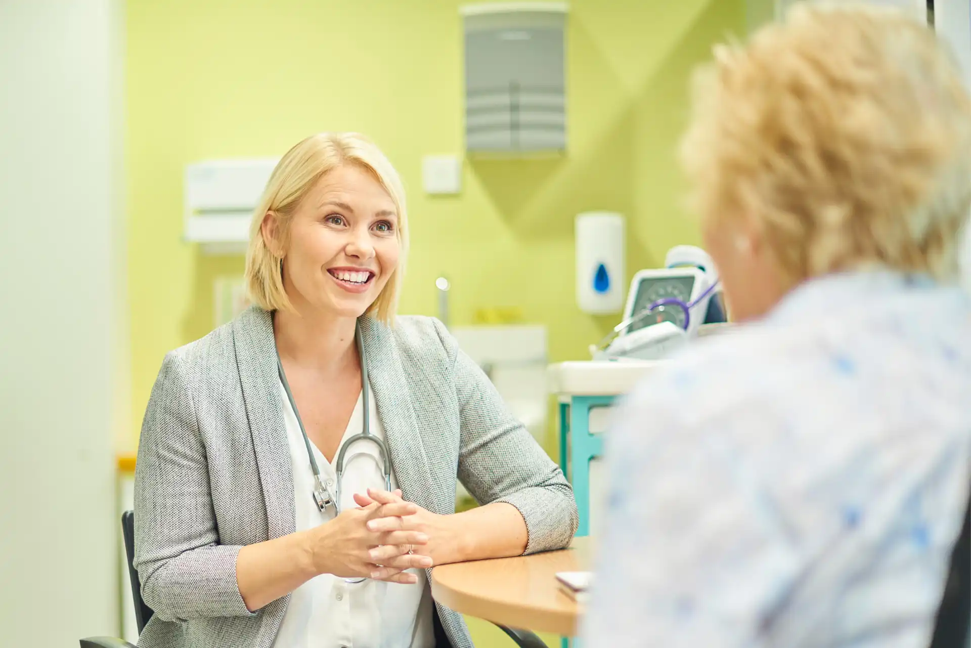 Smiling female doctor with a stethoscope talking to a patient in a clinic.