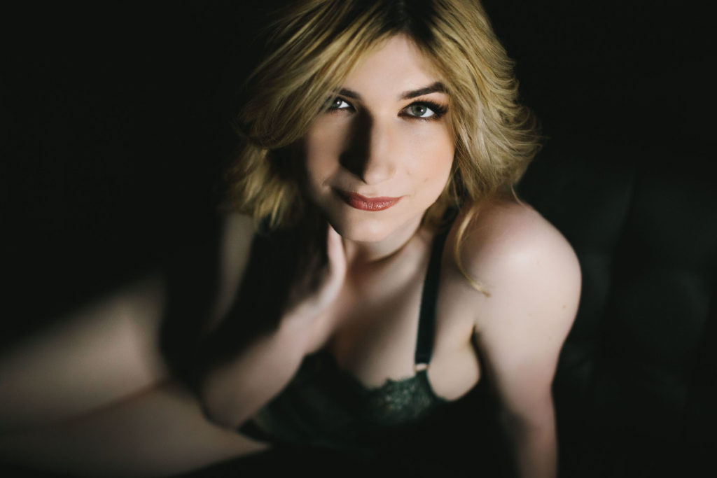 woman in black bra and dark background looking at the camera; through the lens of beauty; boudoir photography by Lindsay Hite