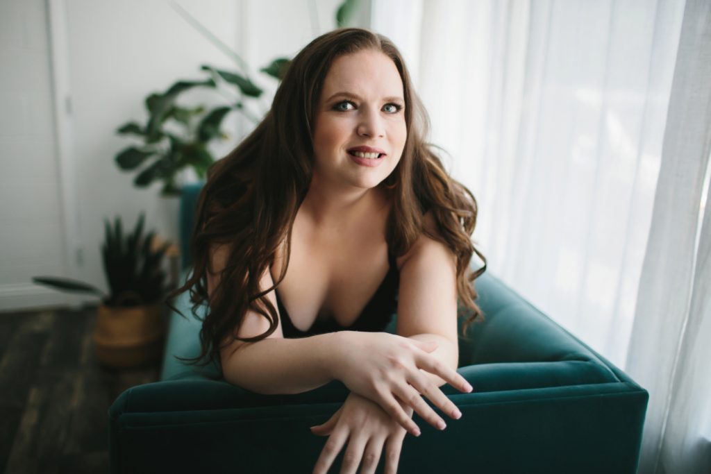 Woman in Black Lingerie on teal couch looking at the camera, Boudoir Photography by Lindsay Hite